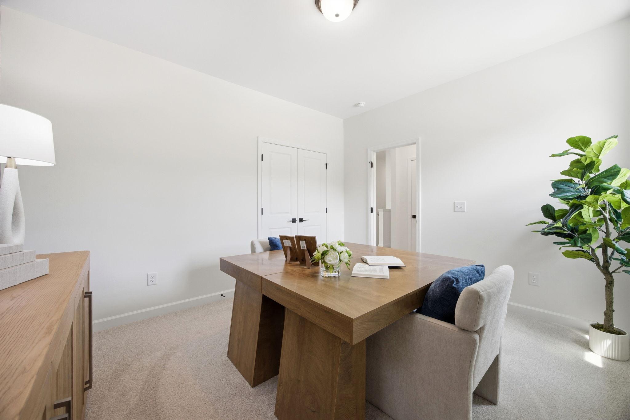 Bright home office space in The Ashport by Davidson Homes featuring a modern wood desk and neutral decor.