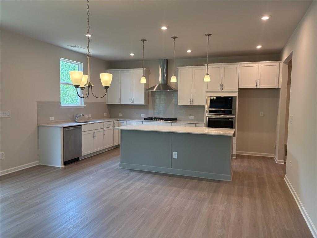 Spacious open-concept kitchen with white cabinets, gray island, stainless appliances in 5-bedroom Davidson Homes The Hickory B, Riverwood, Dallas, GA