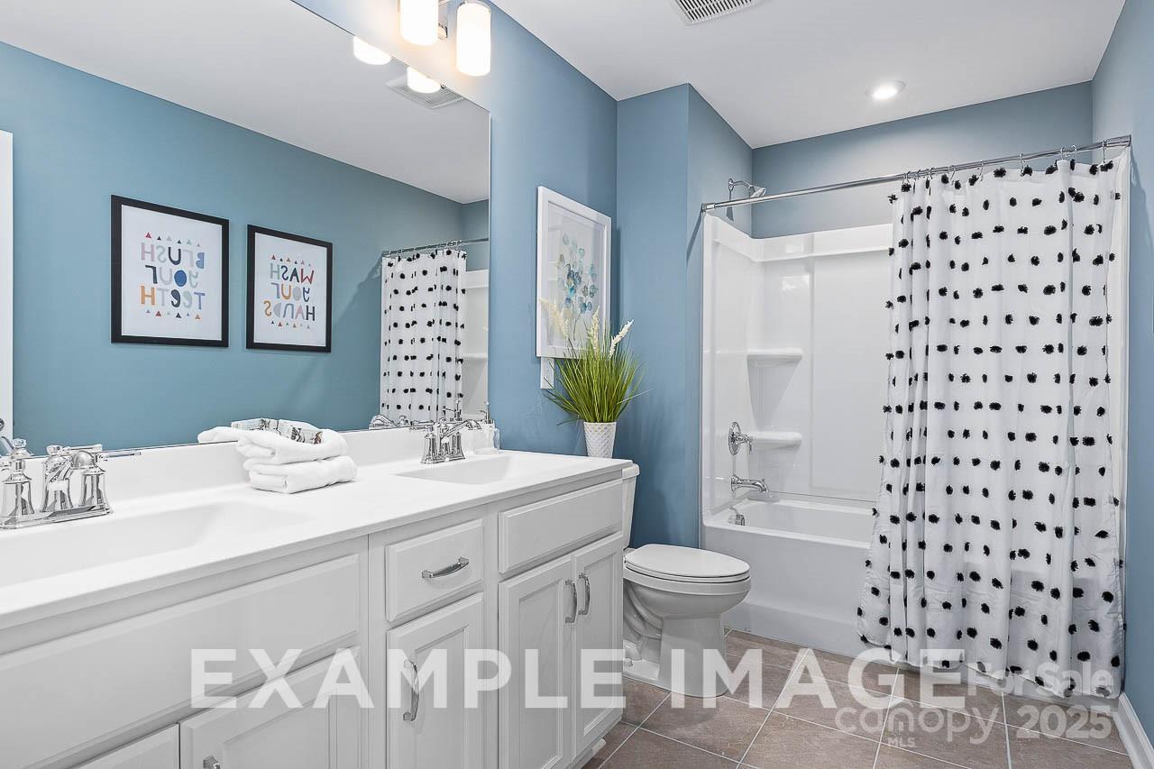 Modern blue bathroom featuring double vanity, polka dot shower curtain in The Hemlock A floor plan, Enclave at Belmont, NC