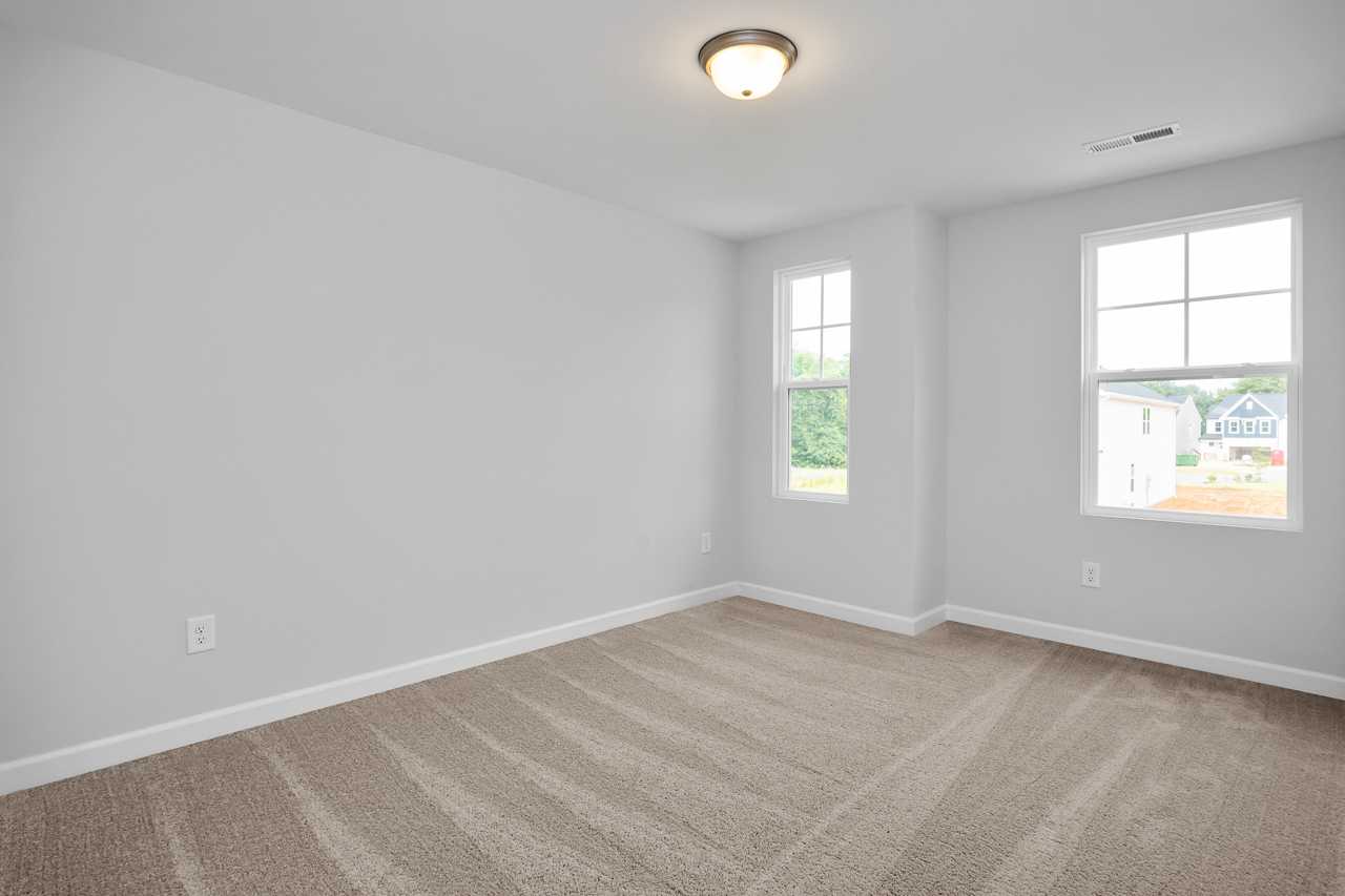 Spacious upstairs bedroom in The Durham D with light gray walls, beige carpet, large windows, and ceiling light