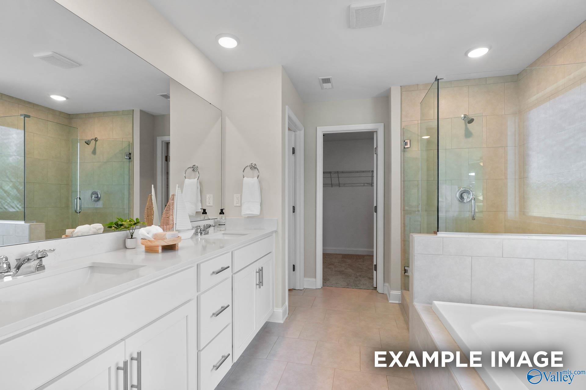 Modern master bathroom with dual vanity, glass-enclosed shower, and soaking tub in The Madison A home, The Meadows, Athens.