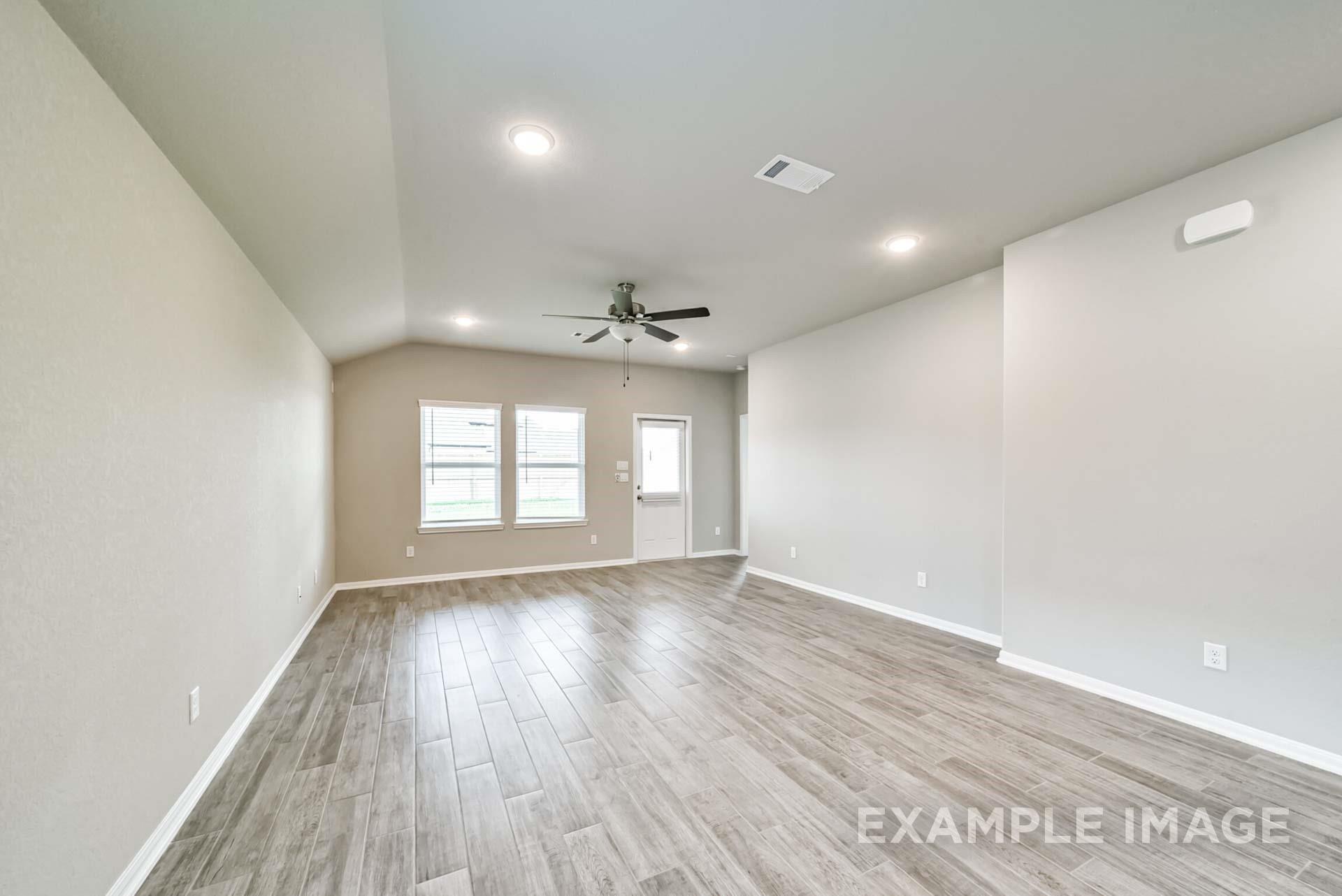 Spacious open-concept living room with wood-look tile flooring in The Riviera A floor plan by Davidson Homes in Emberly.