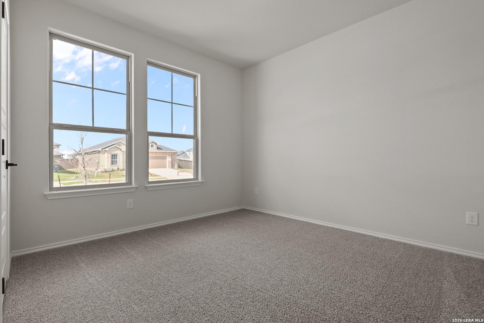 Bright secondary bedroom with large grid windows and green yard view in Davidson Homes The Daphne H, Seguin, Texas