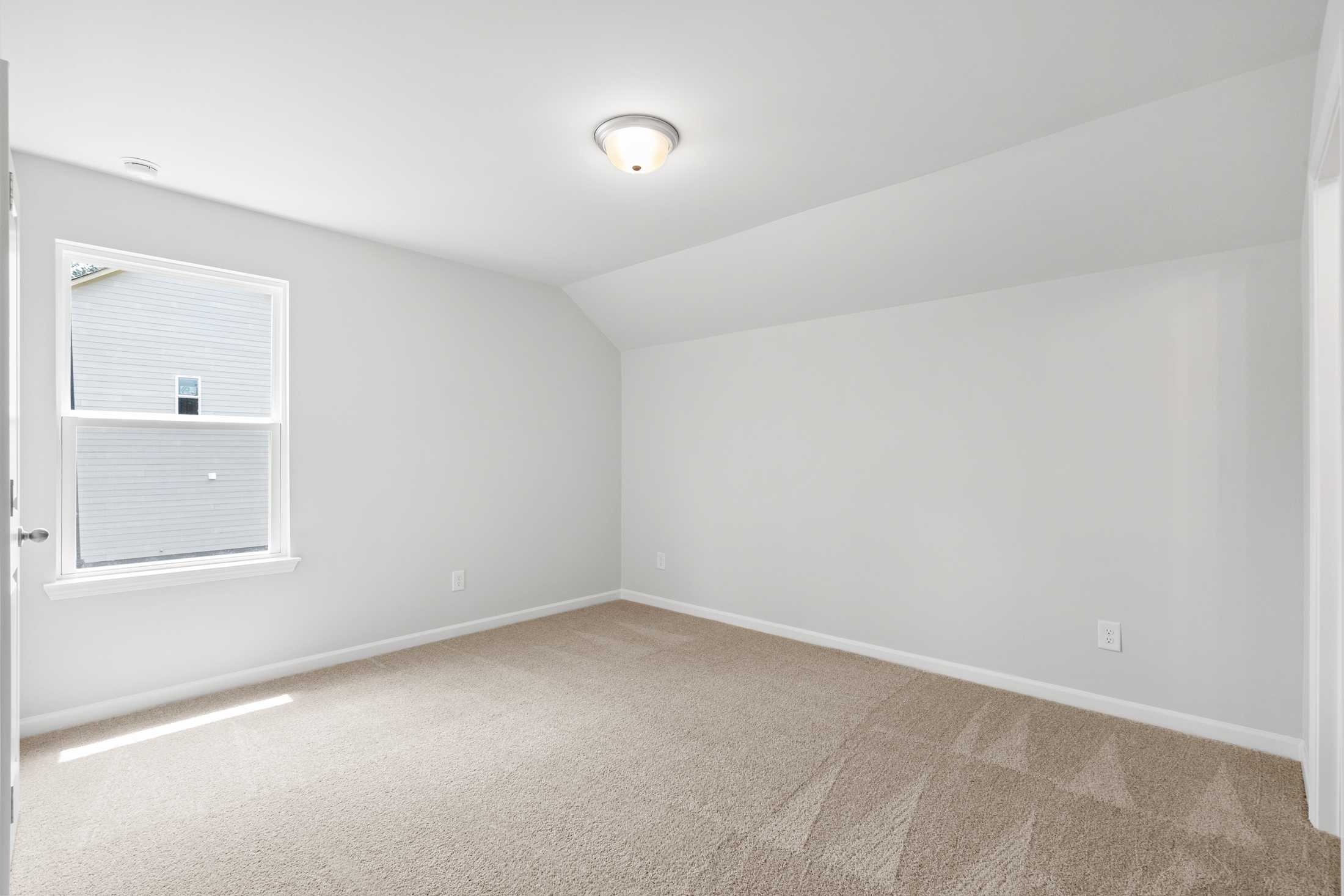 Spacious upstairs bedroom in The Ash B at Wehunt Meadows with beige carpet, white walls, sloped ceiling, and large window