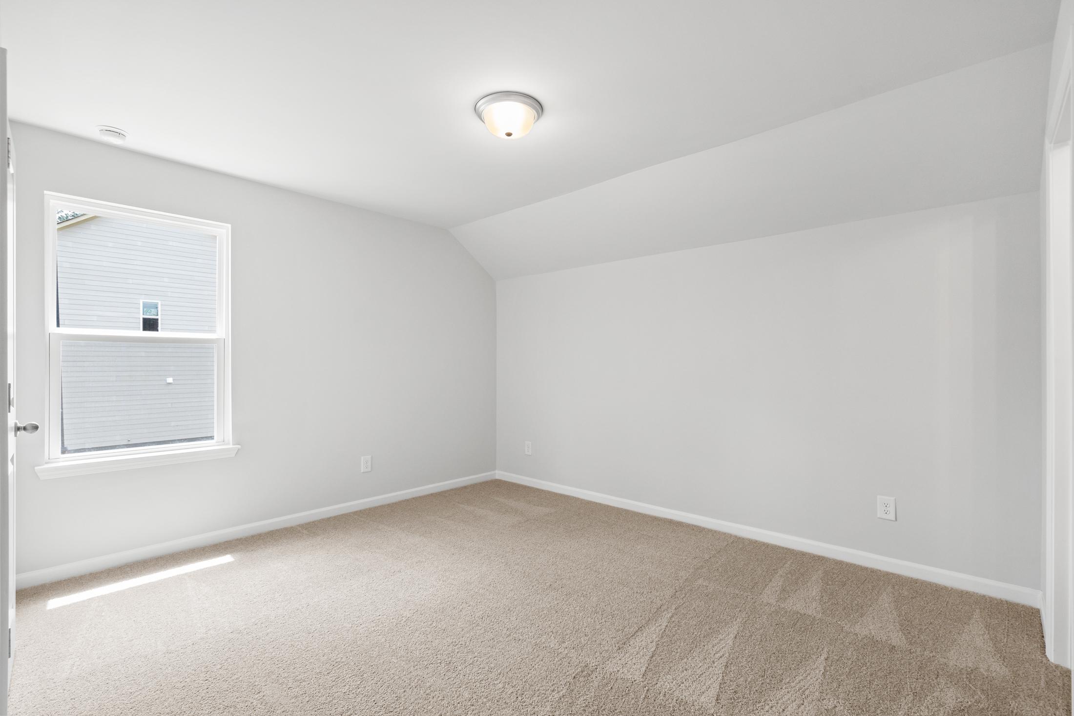 Spacious upstairs bedroom in The Ash B at Wehunt Meadows with beige carpet, white walls, sloped ceiling, and large window