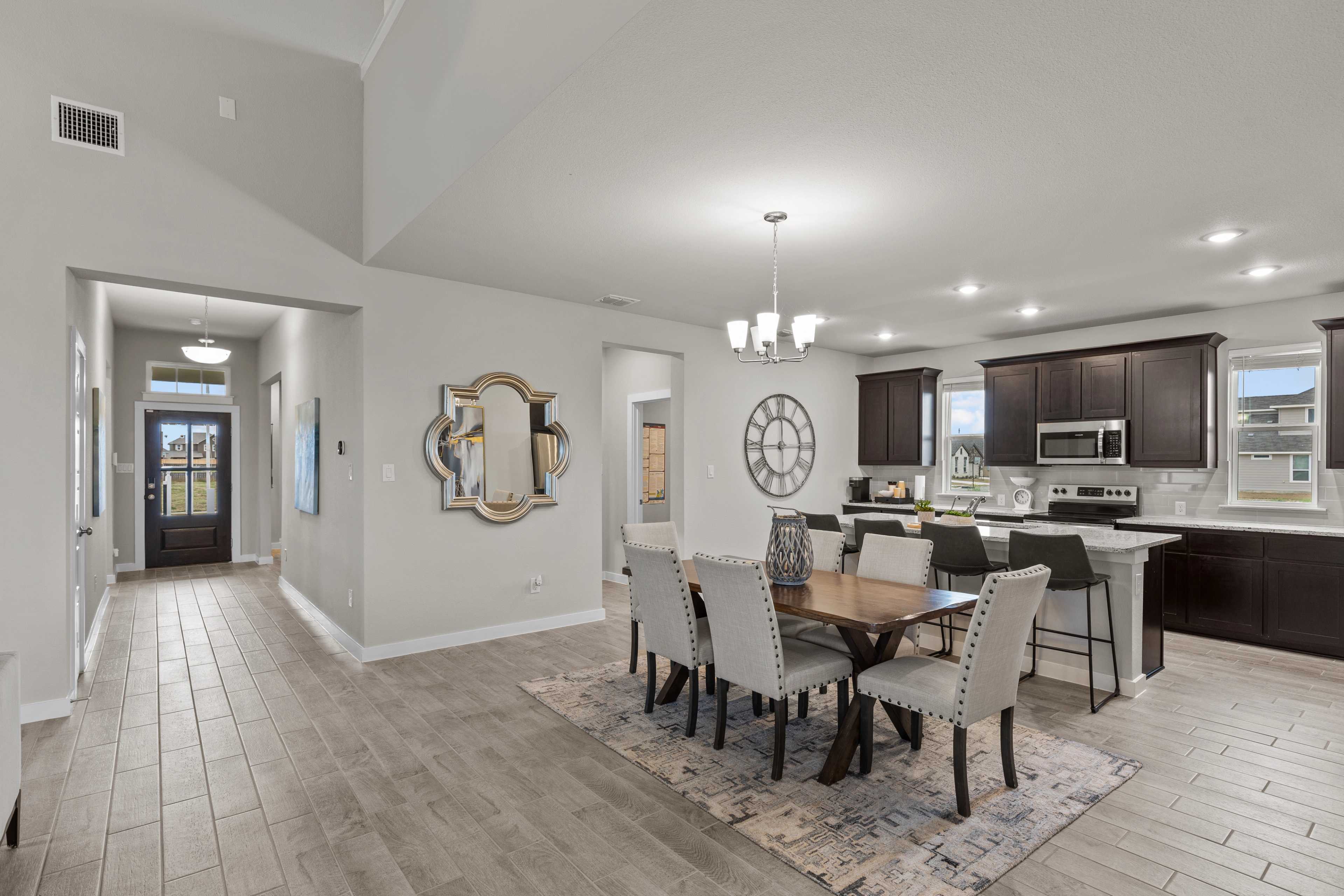 Open-concept kitchen and dining area in Hannah Heights Seguin Texas by Davidson Homes featuring modern island, dining table, and hallway view