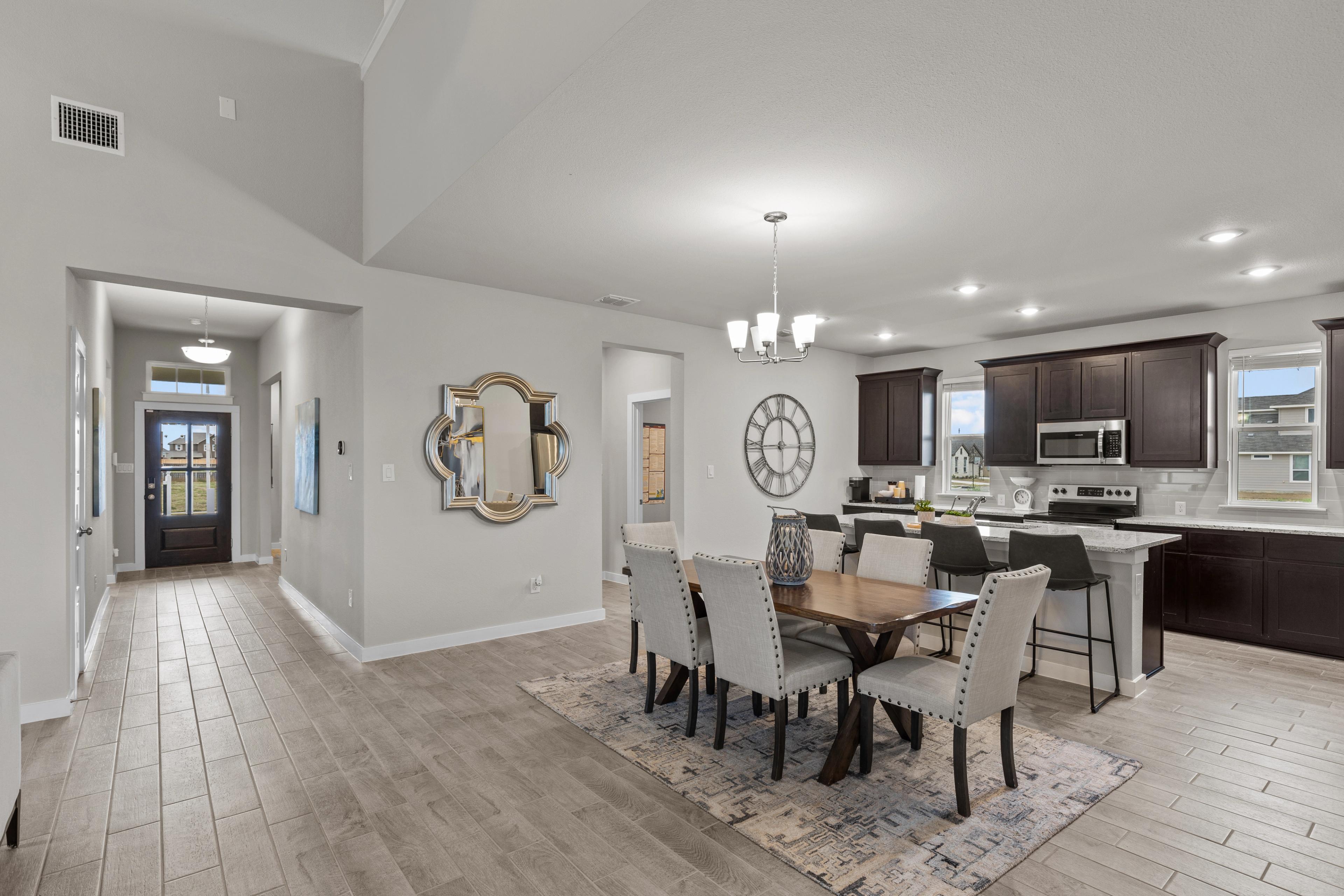 Open-concept kitchen and dining area in Hannah Heights Seguin Texas by Davidson Homes featuring modern island, dining table, and hallway view