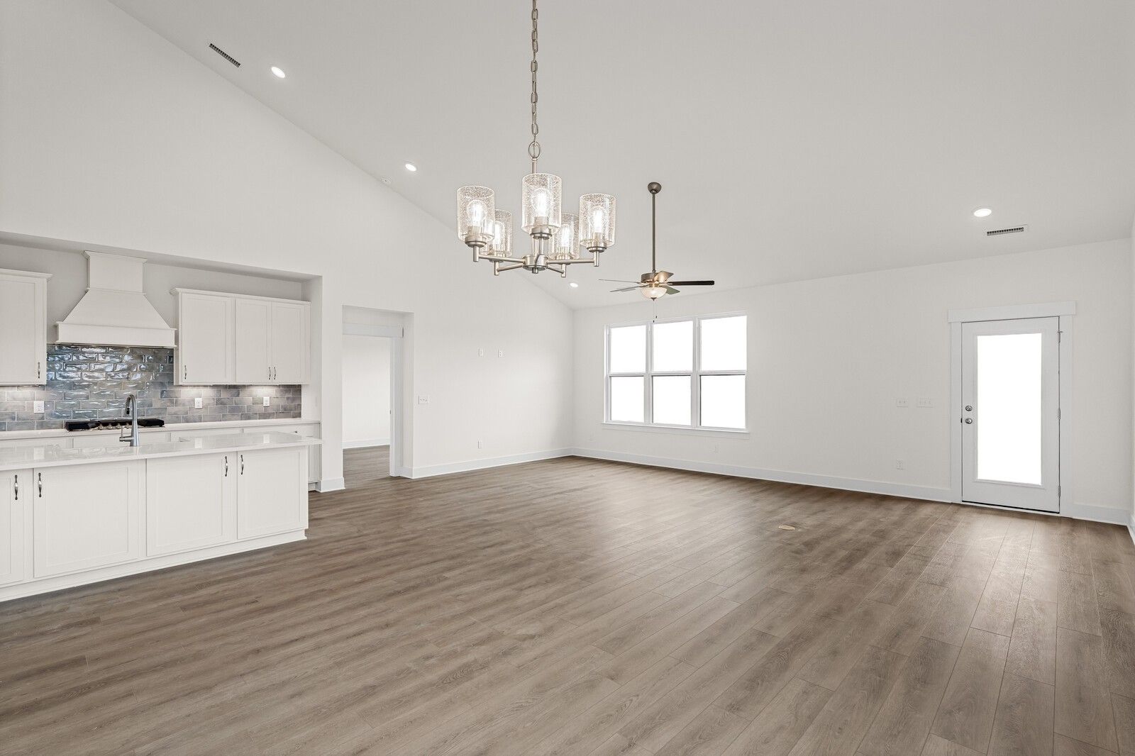 Open-concept kitchen with white cabinets, quartz island, subway tile backsplash, vaulted ceiling in Davidson Homes Ridgeport D, Mt. Juliet TN