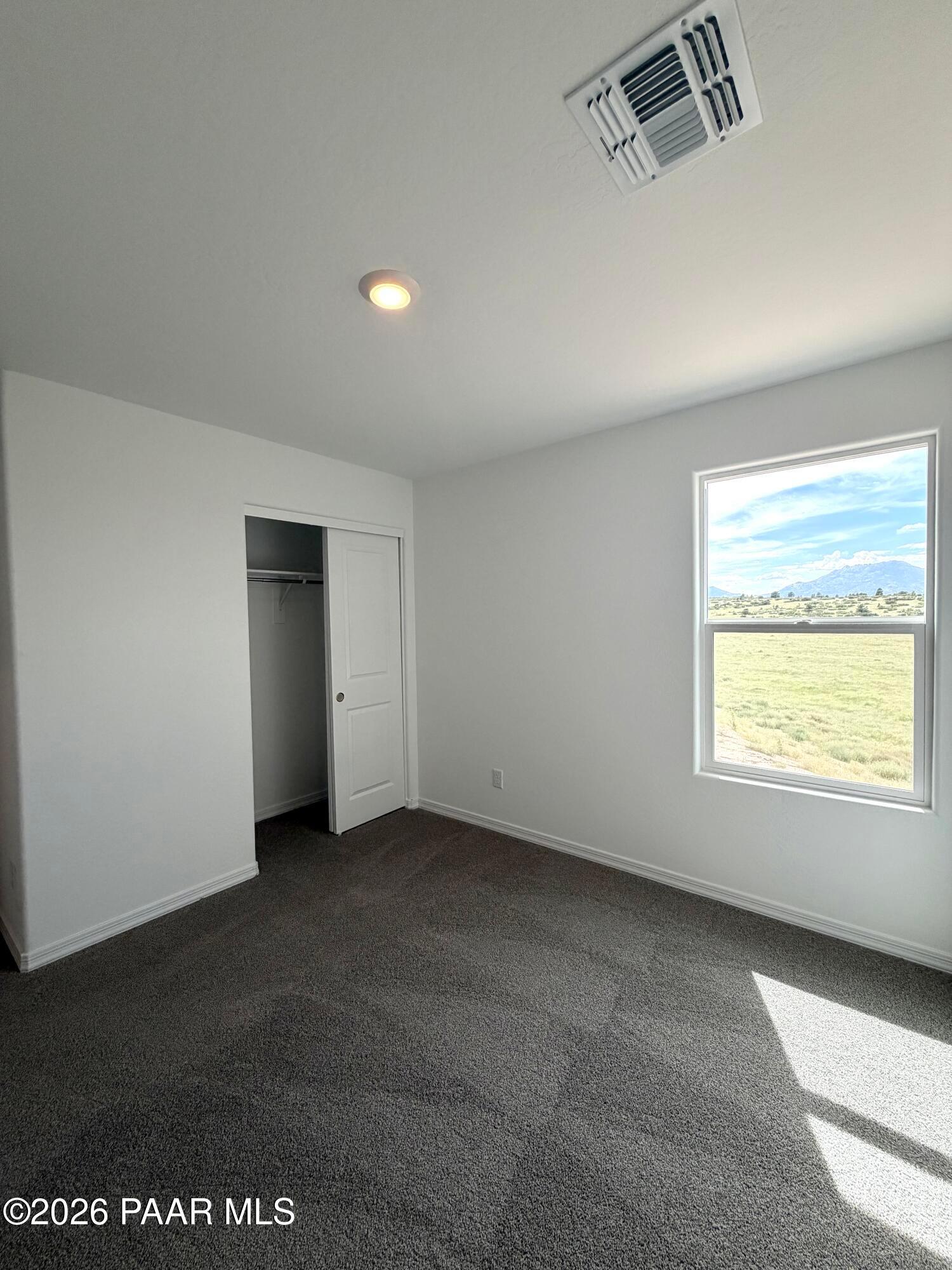 Bright bedroom with carpet, closet, and mountain views in The Raleigh A floor plan at South Ranch, Prescott, Arizona.
