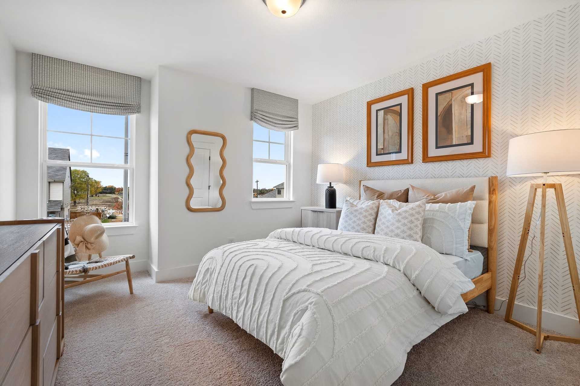 Cozy children's bedroom with ruffled white bedding, chevron walls, wavy mirror, and large windows in Davidson Homes The Wake D, Wylie, Texas