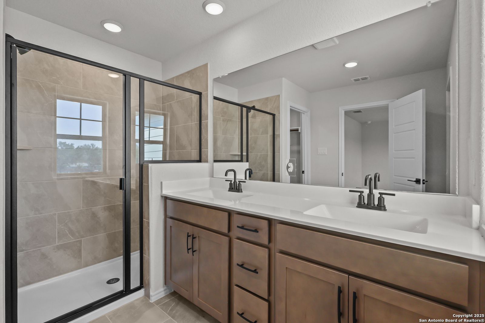 Spacious master bathroom with glass shower enclosure, double vanity, and recessed lighting in Davidson Homes The Florence C, San Antonio