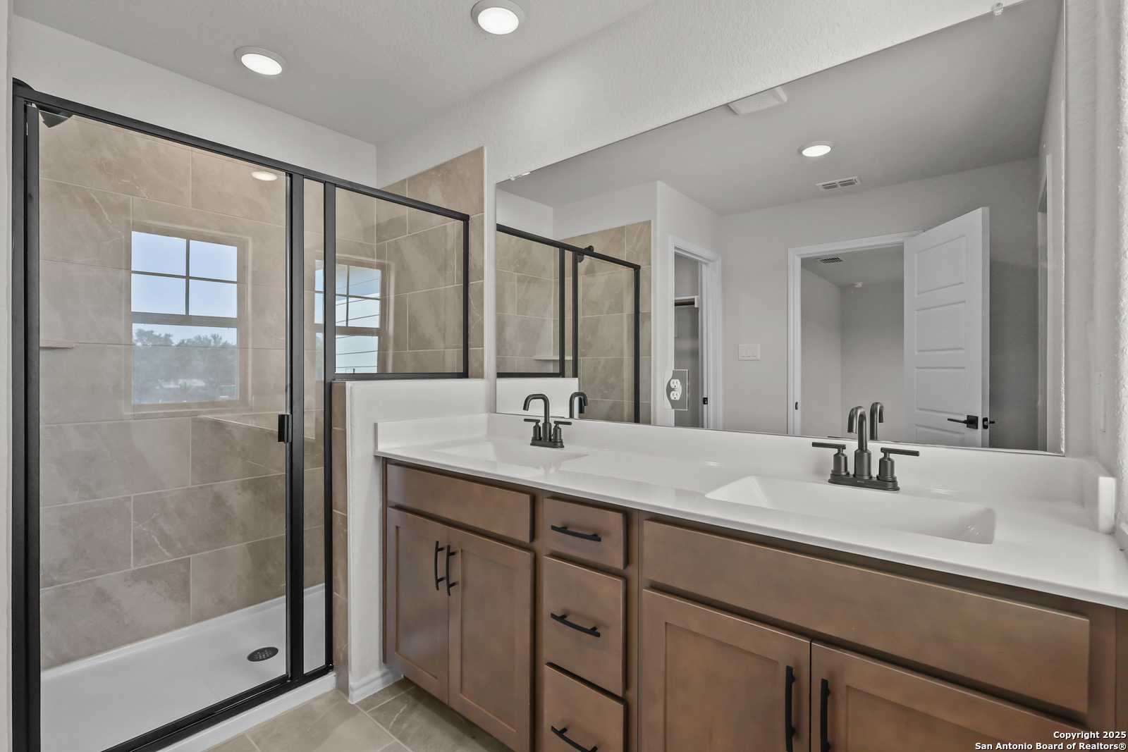 Spacious master bathroom with glass shower enclosure, double vanity, and recessed lighting in Davidson Homes The Florence C, San Antonio