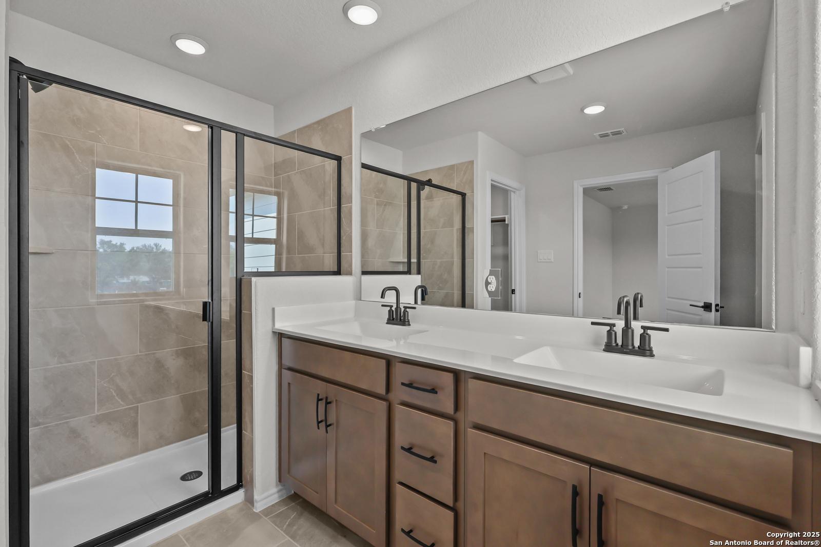 Spacious master bathroom with glass shower enclosure, double vanity, and recessed lighting in Davidson Homes The Florence C, San Antonio