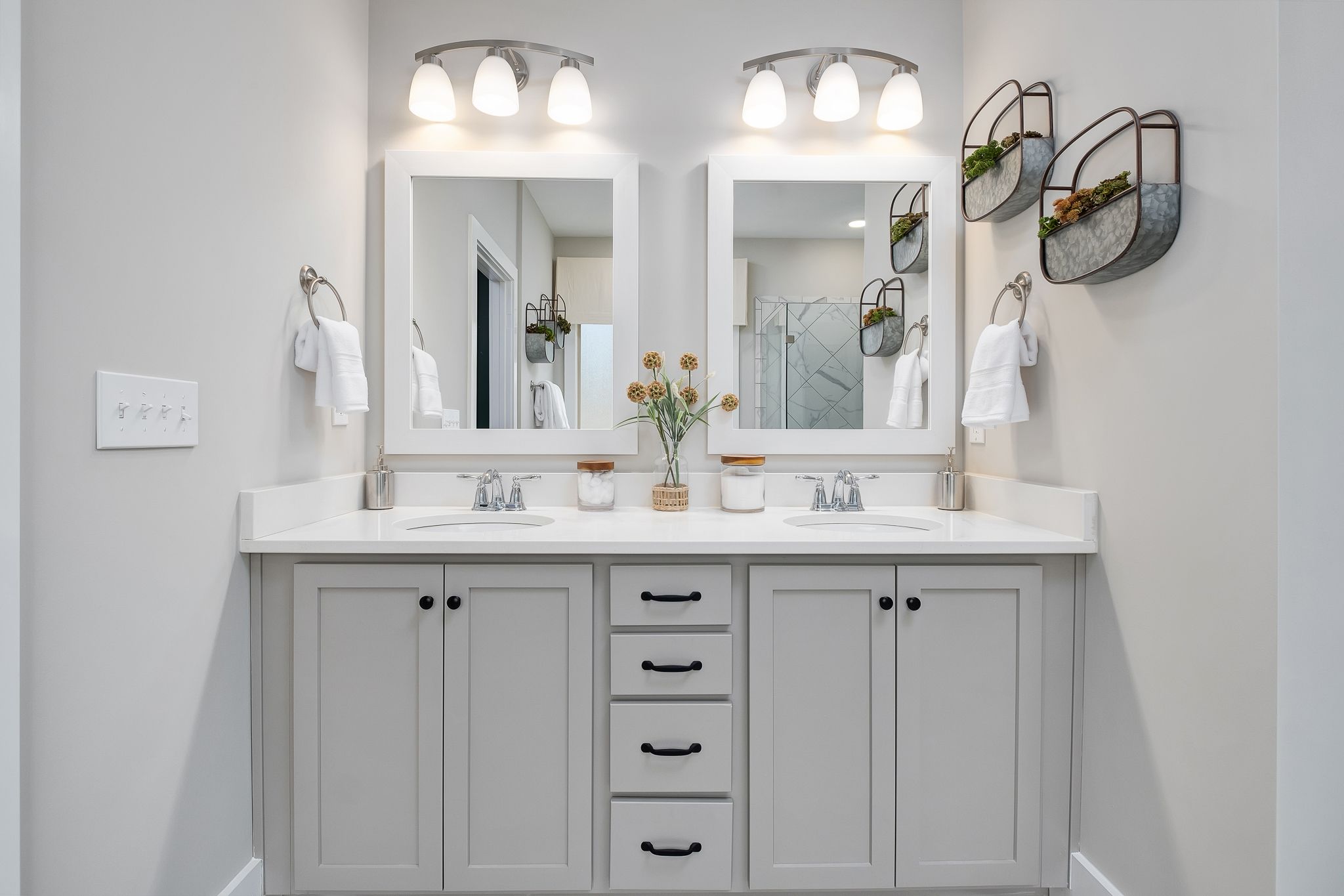 Modern gray double vanity bathroom at Chimney Creek in Hampton Cove Alabama with quartz counters, mirrors and decorative planters