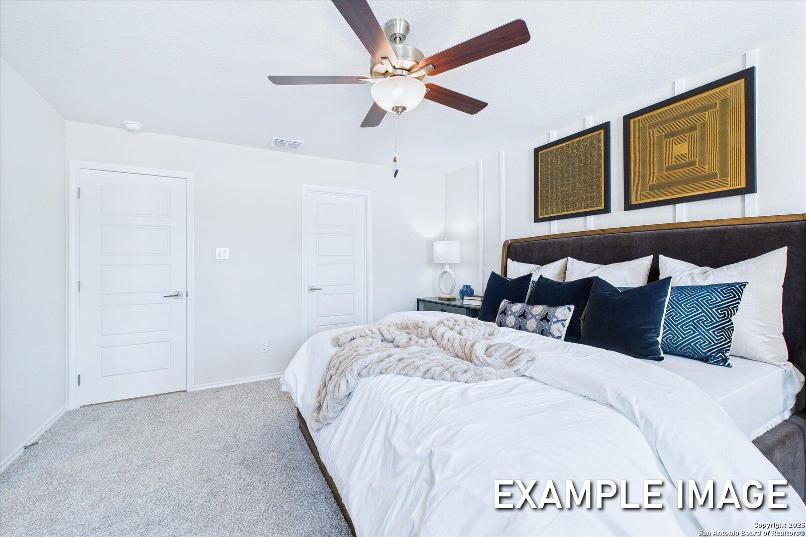 Luxurious master bedroom with plush king bed, ceiling fan, and modern art in Davidson Homes The Gillian B, San Antonio, Texas