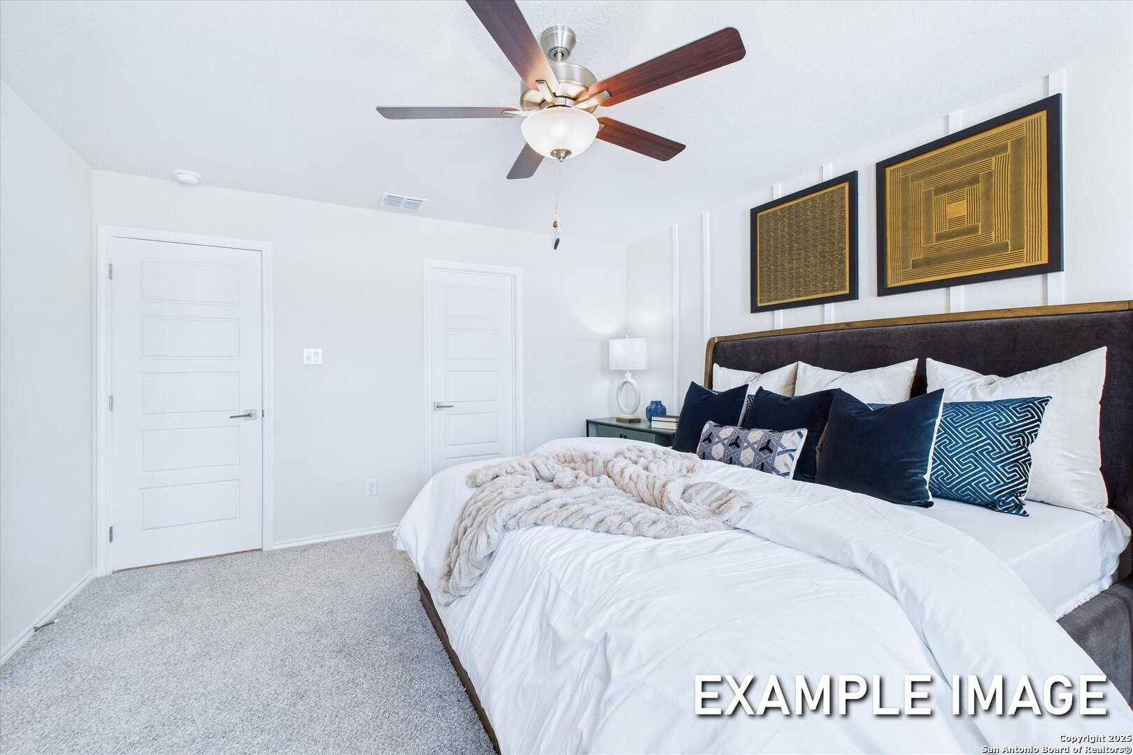 Cozy secondary bedroom with ceiling fan, double closets, plush bed and pillows in Davidson Homes The Gillian C, San Antonio