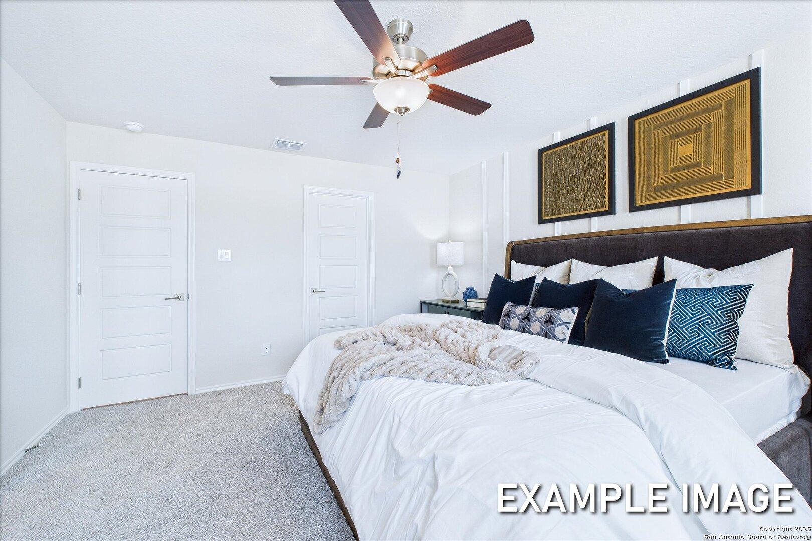 Elegant master bedroom with ceiling fan, king bed, colorful pillows, and dual closets in Davidson Homes The Gillian C, San Antonio