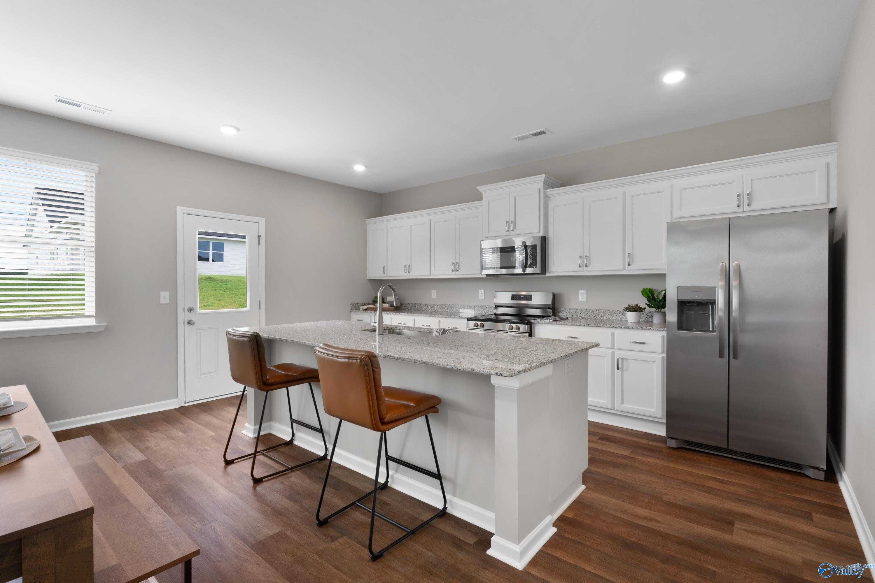 Modern kitchen with white shaker cabinets, granite island, stainless steel appliances in Evermore Homes The Noble, Madison AL
