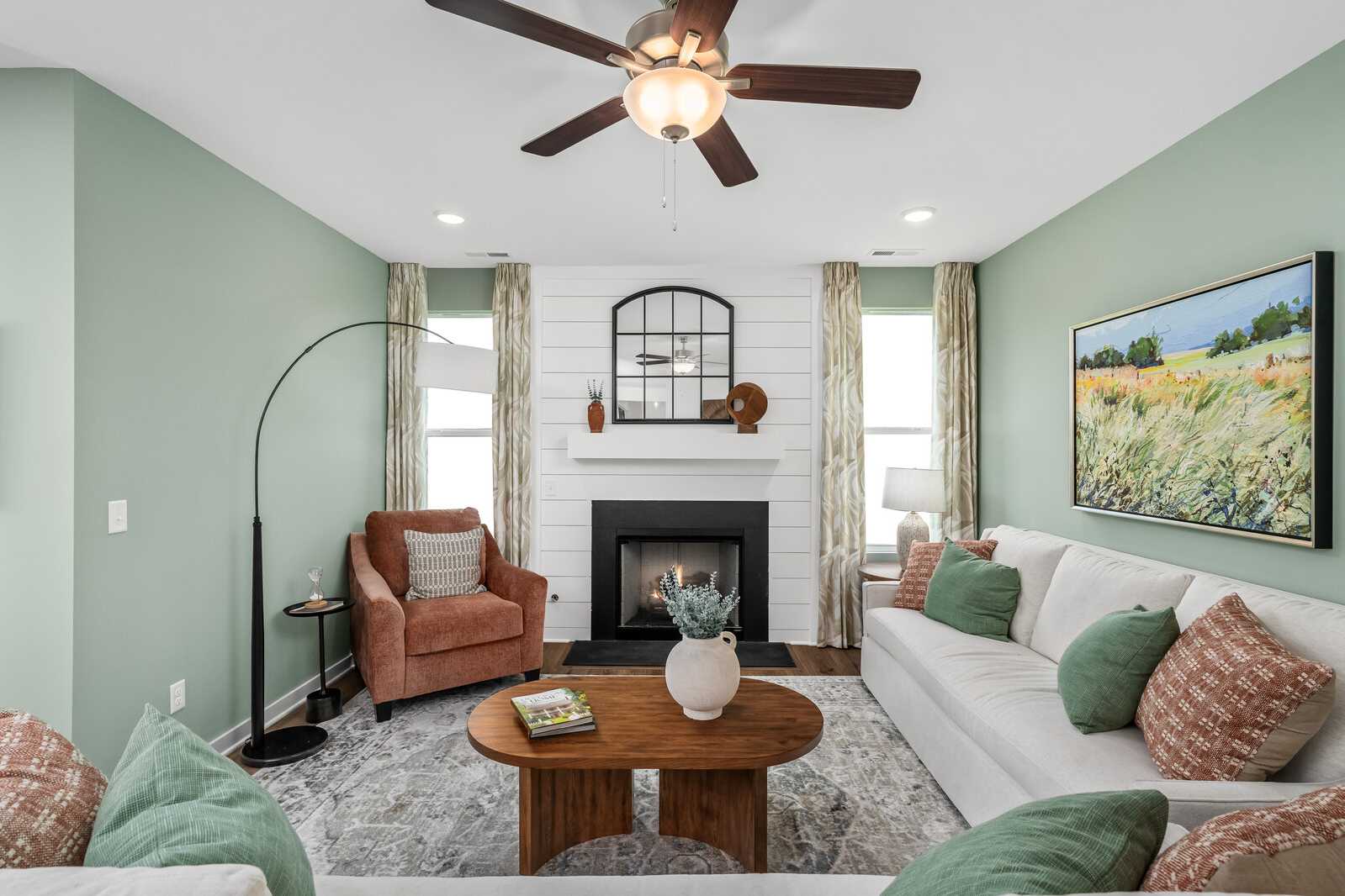 Cozy living room at Calista Farms in White House TN with sage green walls, white sofa, fireplace, and landscape painting