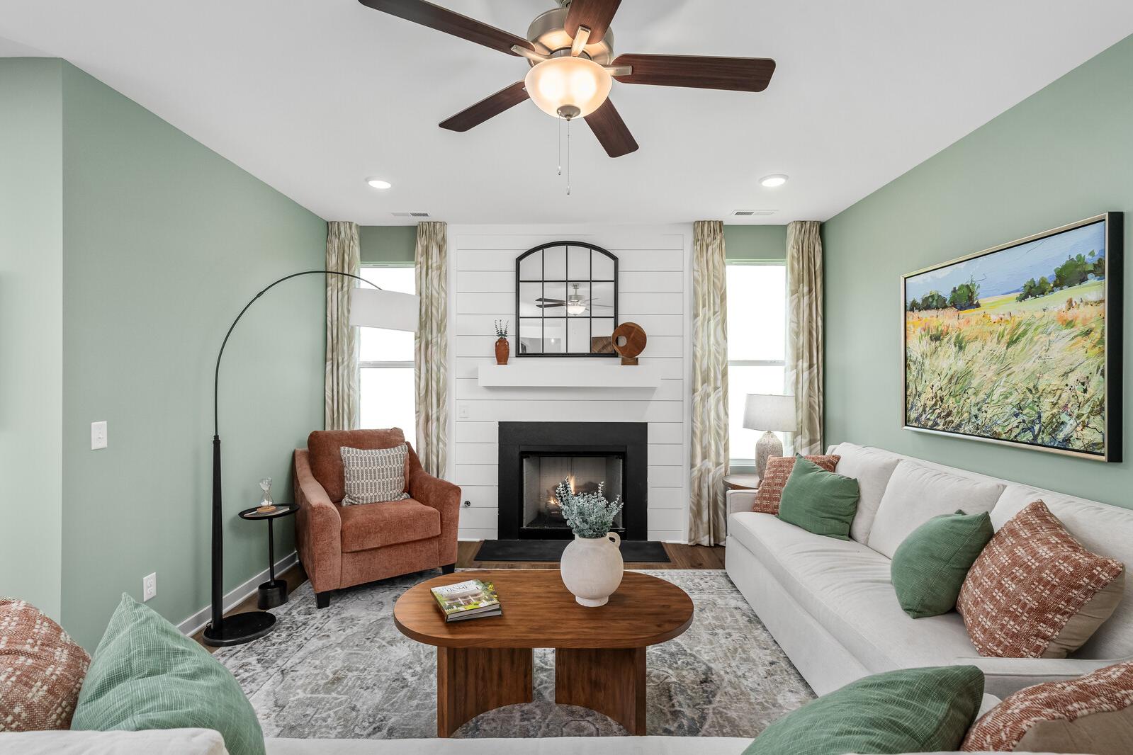 Cozy living room at Calista Farms in White House TN with sage green walls, white sofa, fireplace, and landscape painting