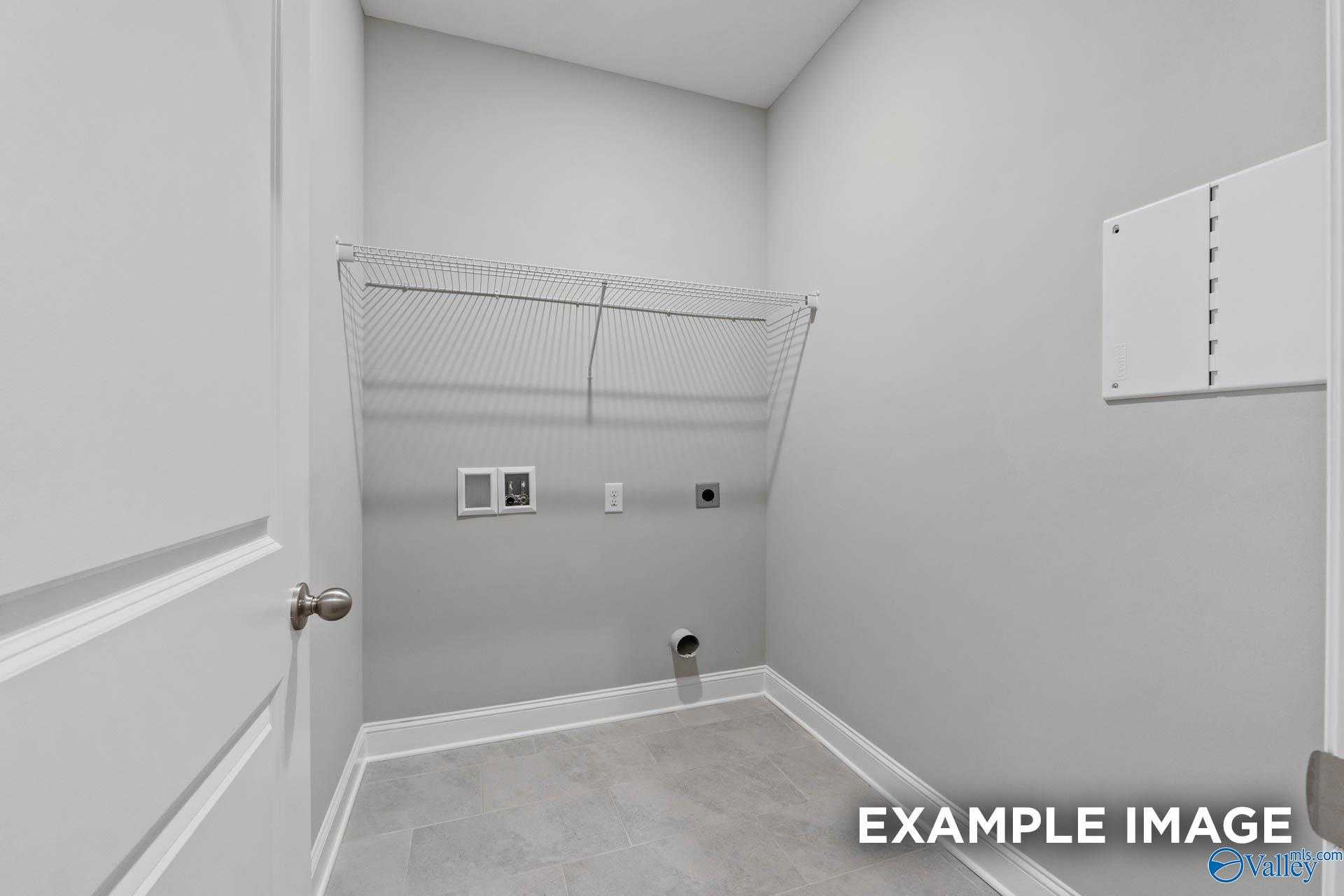 Functional laundry room with wire shelving, hookups, and gray tile floor in Davidson Homes The Montgomery, Pikes Ridge, Meridianville, AL