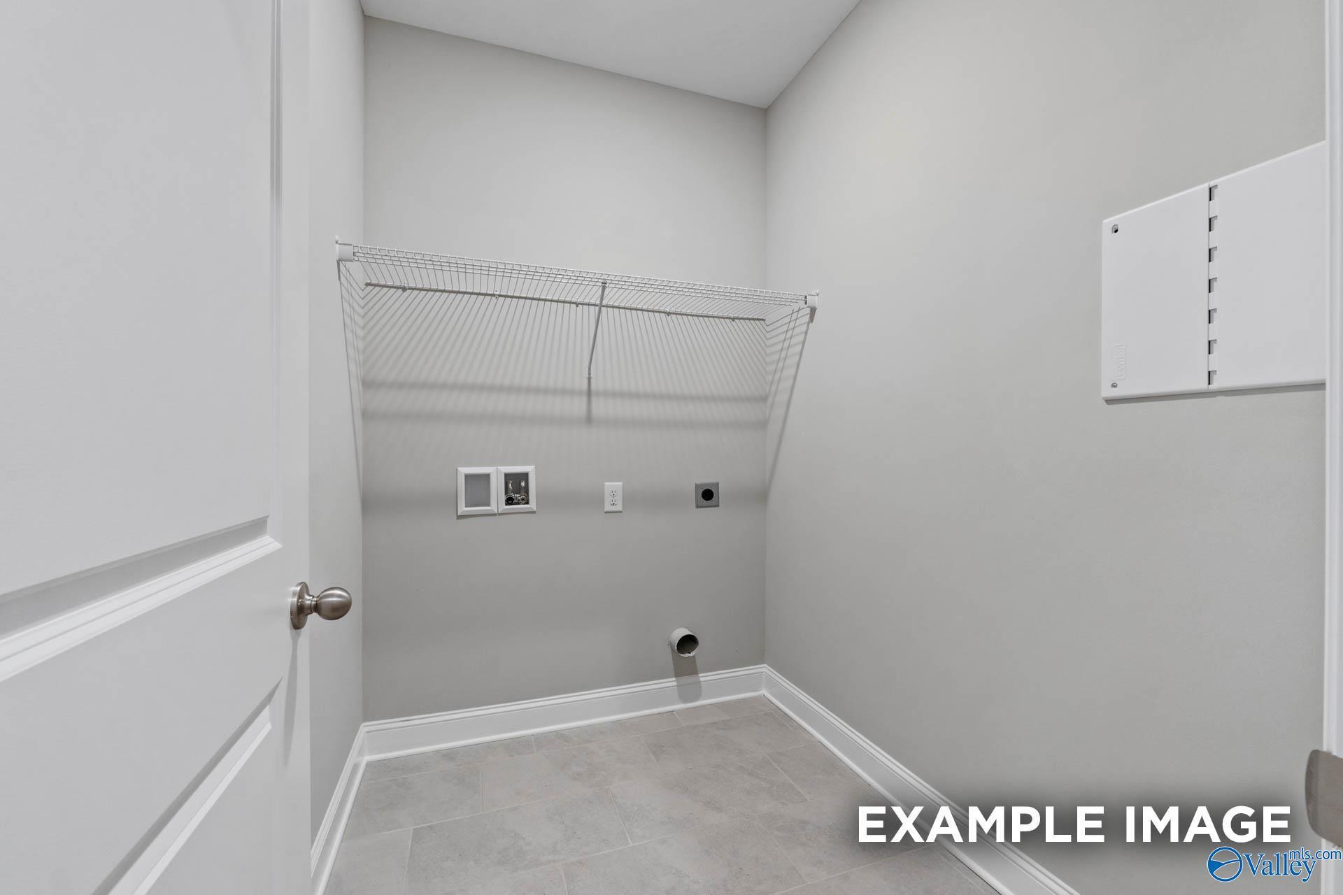 Functional laundry room with wire shelving, hookups, and gray tile floor in Davidson Homes The Montgomery, Pikes Ridge, Meridianville, AL