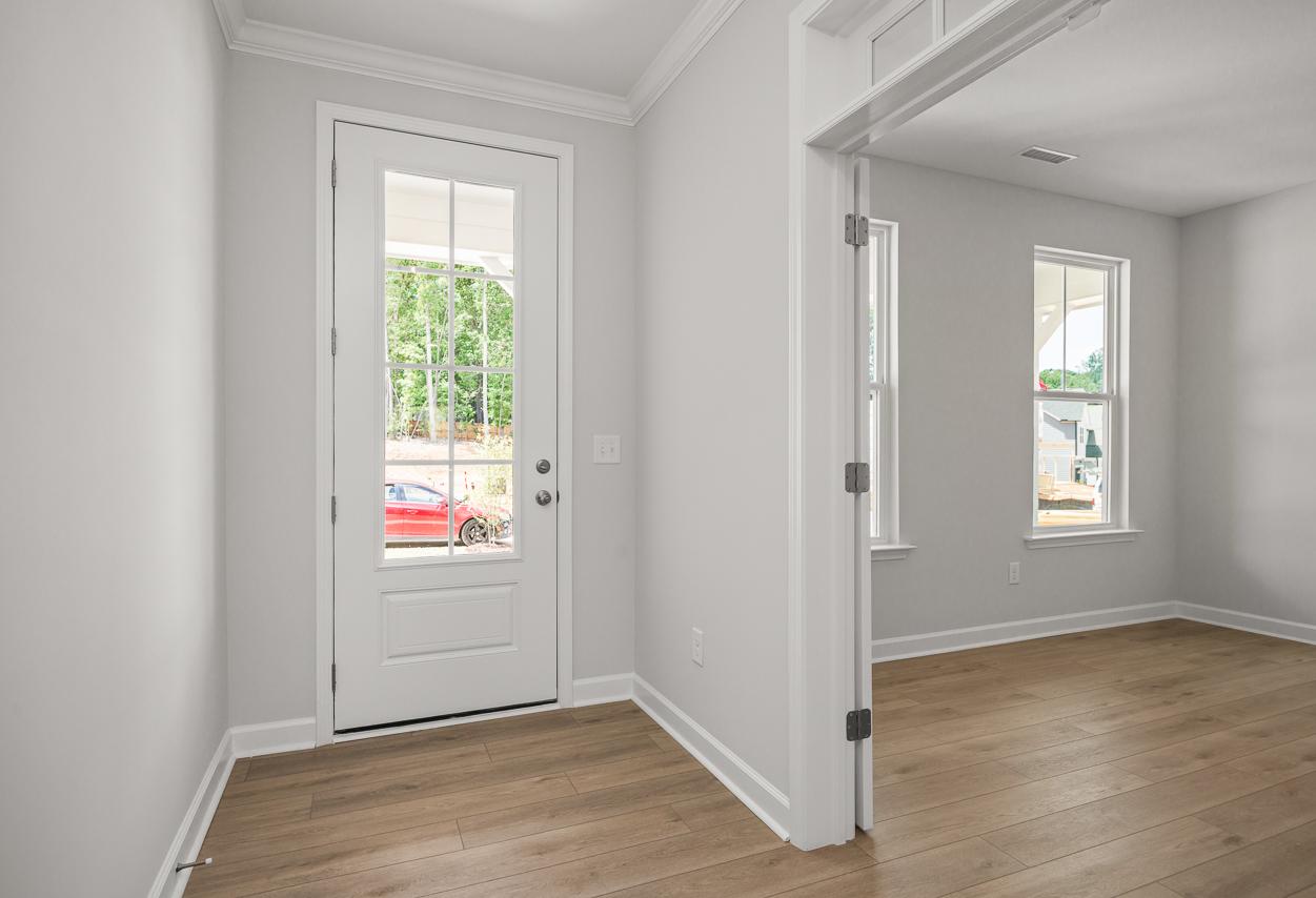 Bright and modern entryway in The Birch II with light wood flooring, glass-paneled front door, and double-door office.