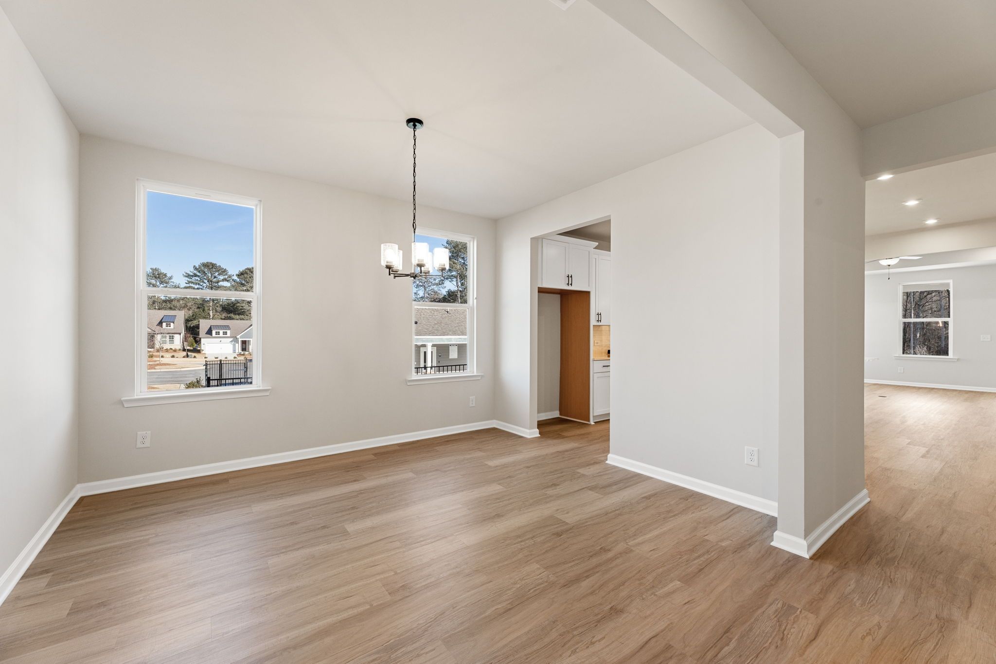 Bright dining room with hardwood floors, chandelier, and large windows in The Glenwood C by Davidson Homes, Loganville, GA