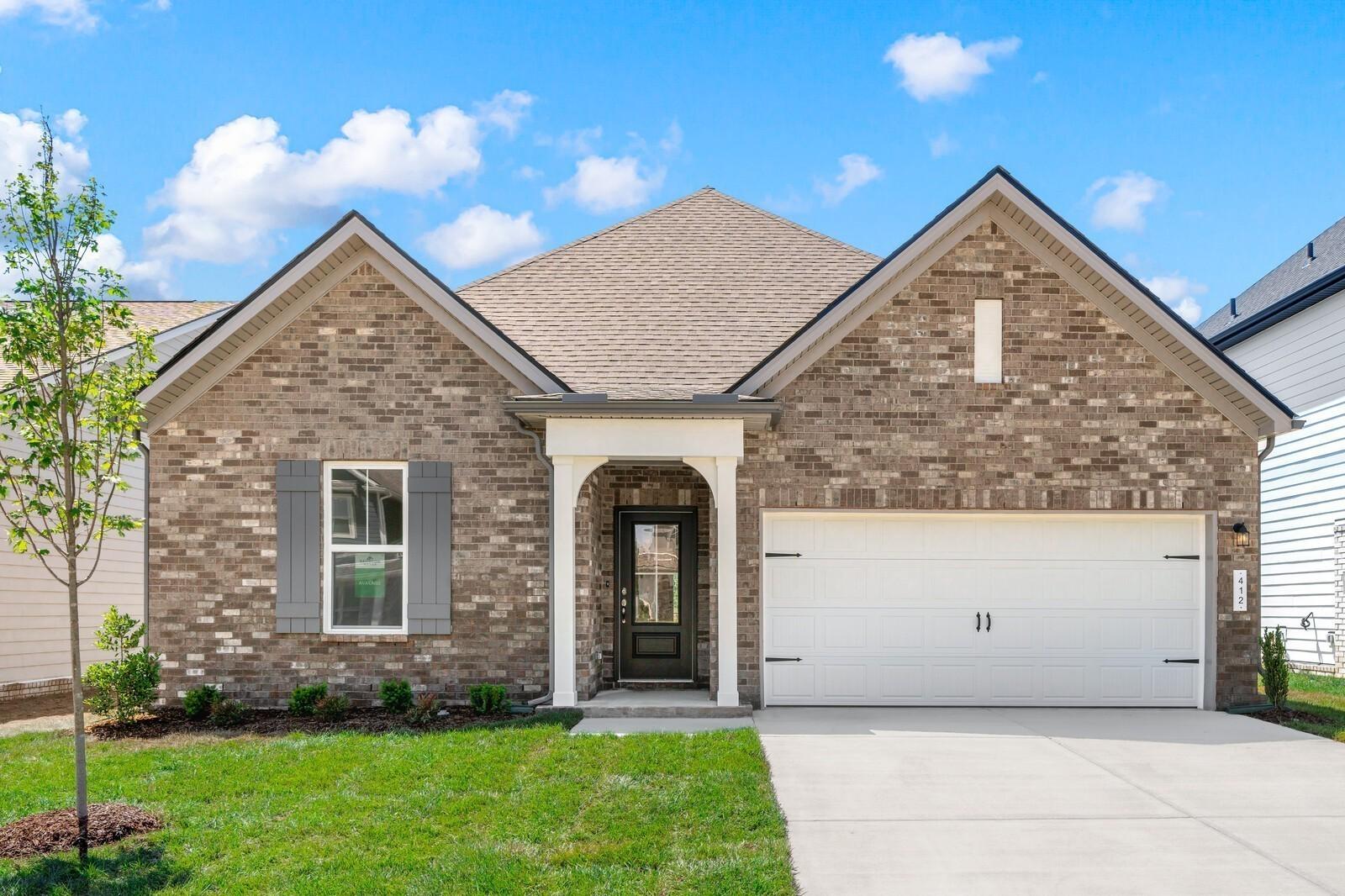 Brick front exterior with 2-car garage and covered porch at The Cottonwood E by Davidson Homes in Woods Crossing, Gallatin, TN