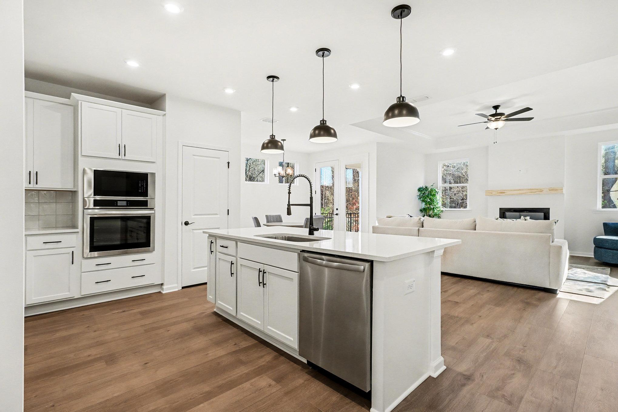 Modern kitchen featuring white shaker cabinets, stainless steel range hood, gas cooktop, and marble backsplash in The Daphne B, Loganville, GA