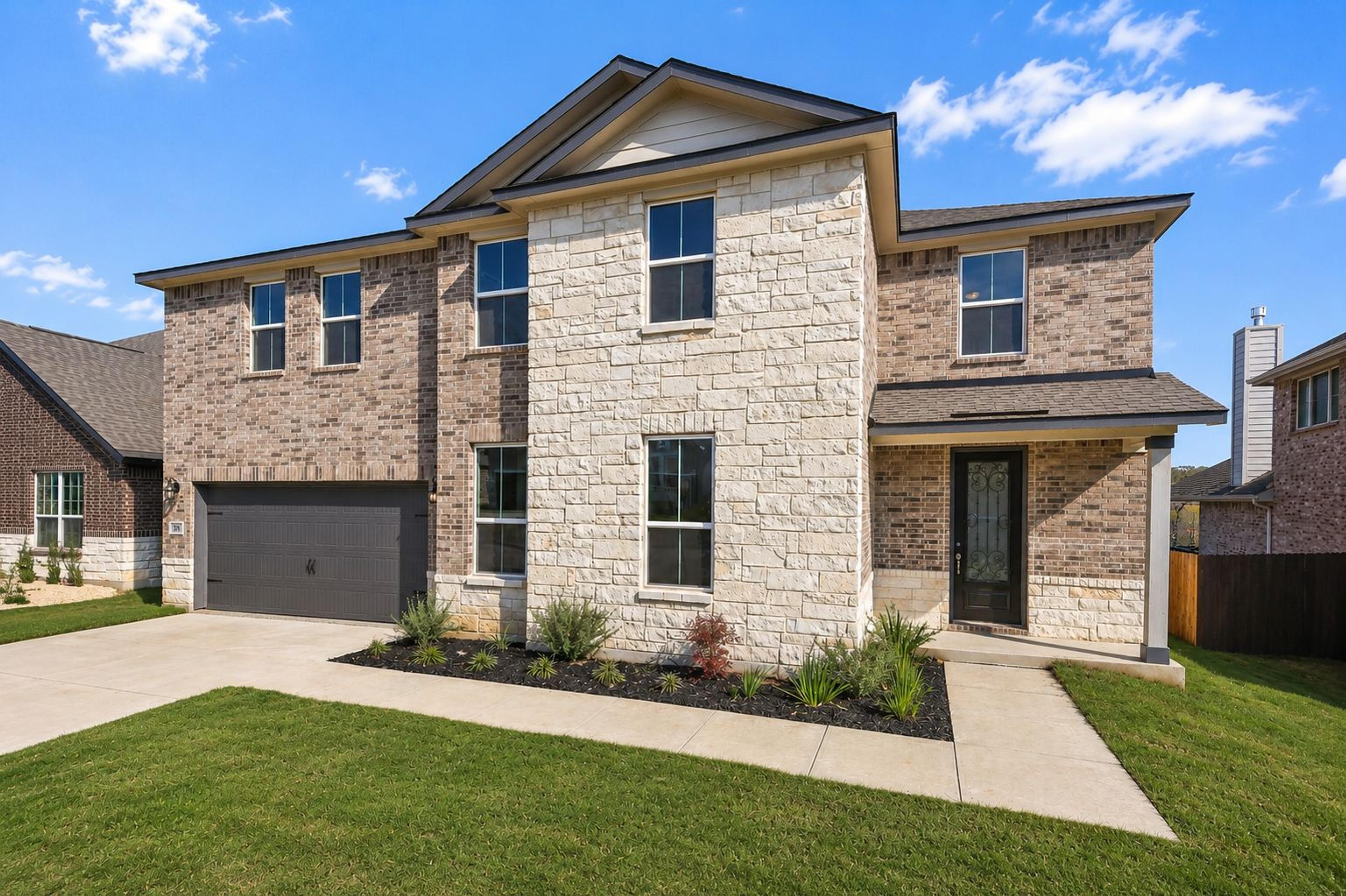 Modern kitchen with quartz island, gray shaker cabinets, and stainless appliances at The Reserve at Potranco Oaks in Castroville, Texas