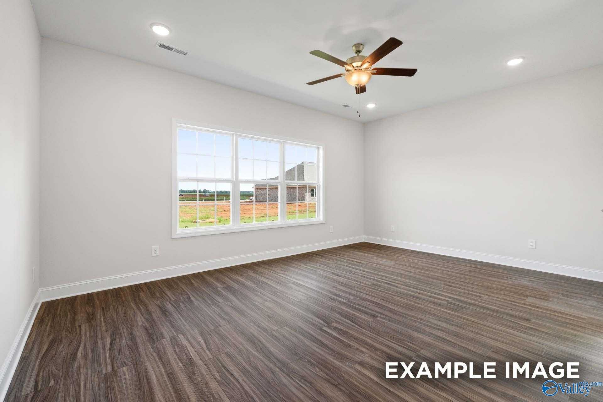 Bright living room with large windows overlooking green fields and barn, ceiling fan, hardwood floors in The Montgomery by Davidson Homes, Athens AL