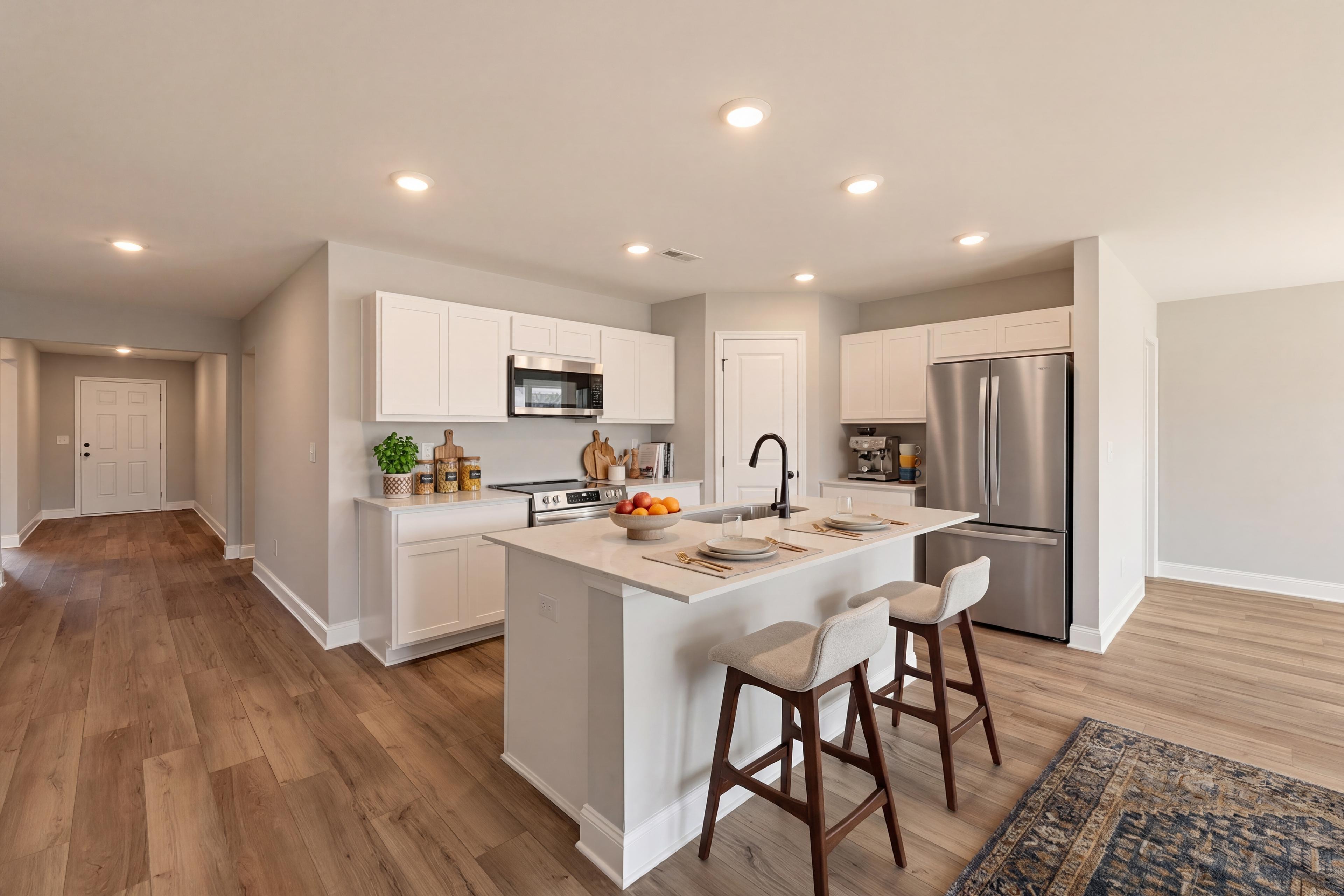 Open-concept kitchen at Chapel Hill in Athens Alabama with white cabinets quartz island stainless appliances hardwood floors