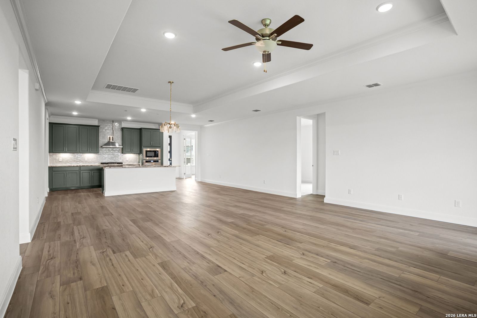 Open-concept living room and kitchen with wood-look floors in The Lanier G floor plan at The Reserve at Potranco Oaks.