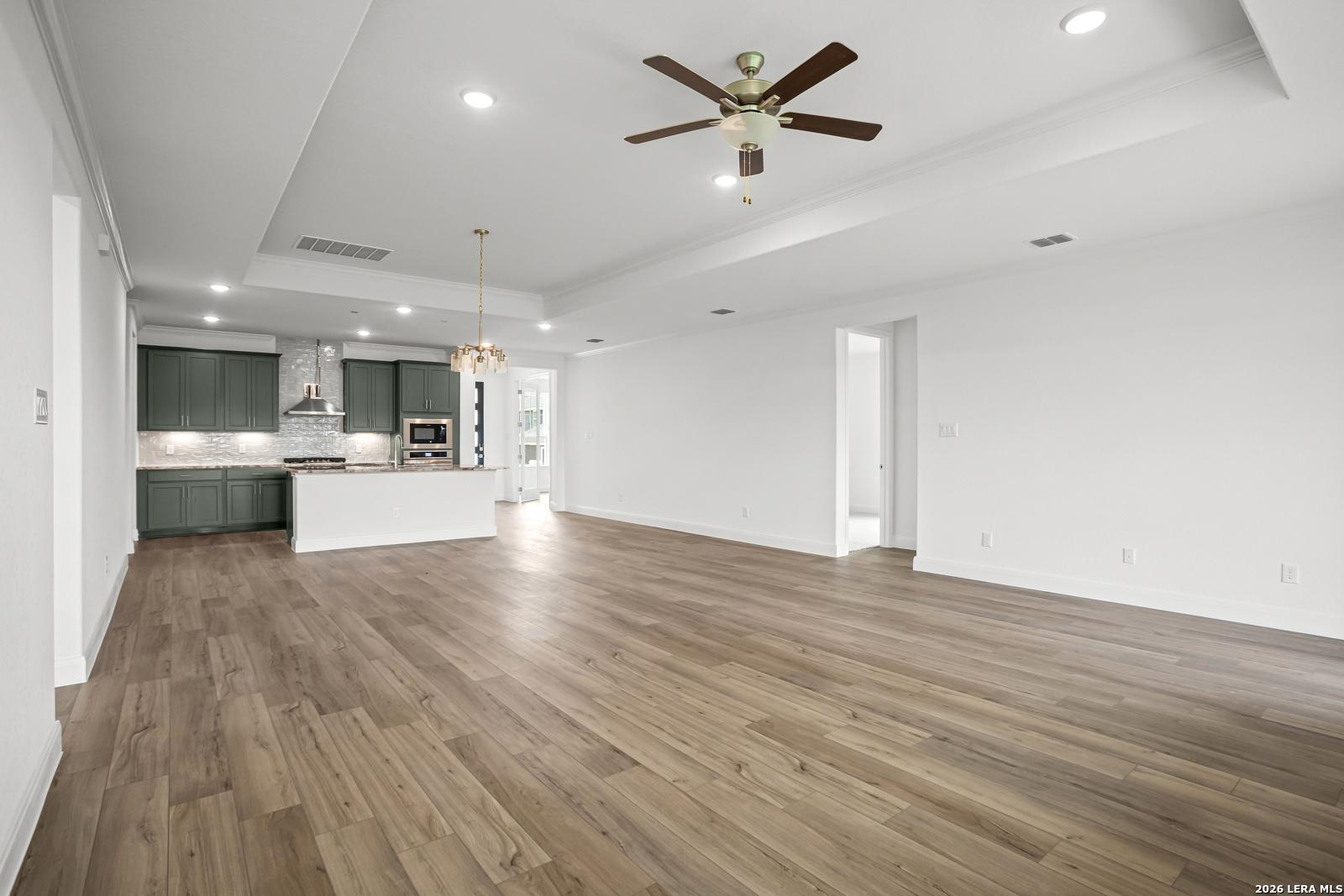 Open-concept living room and kitchen with wood-look floors in The Lanier G floor plan at The Reserve at Potranco Oaks.