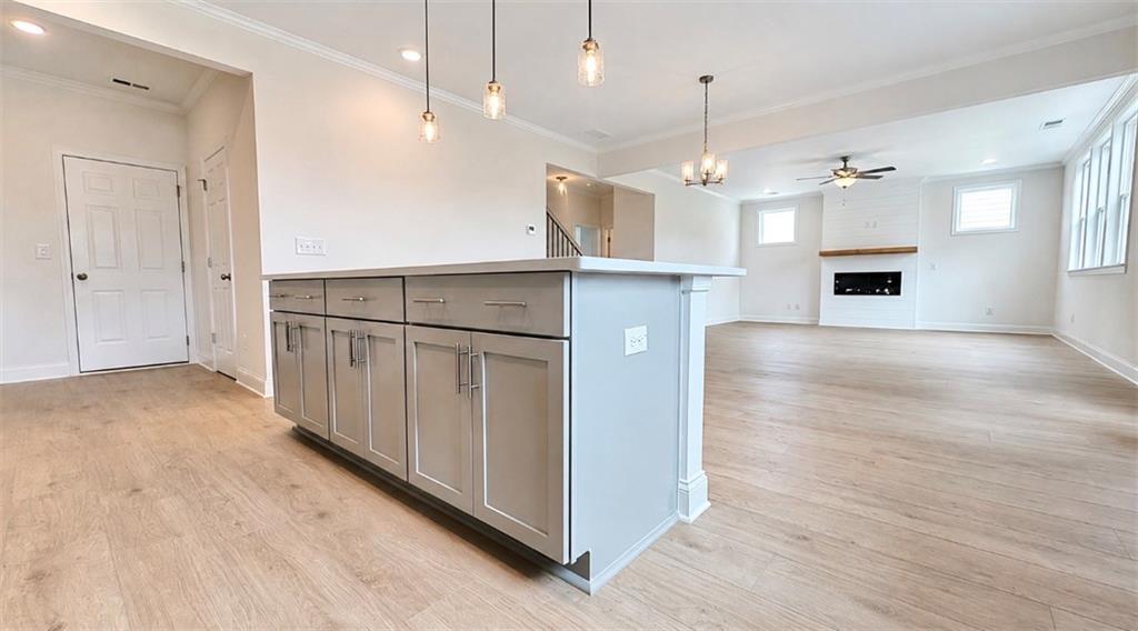 Open-concept kitchen island and spacious living room with fireplace in The Hickory C floor plan at Wehunt Meadows, Hoschton.