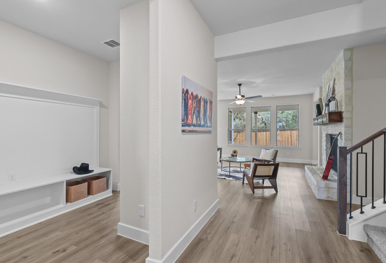Open-concept living area in The Belmont G featuring a stone fireplace, wood flooring, and built-in storage in Castroville.
