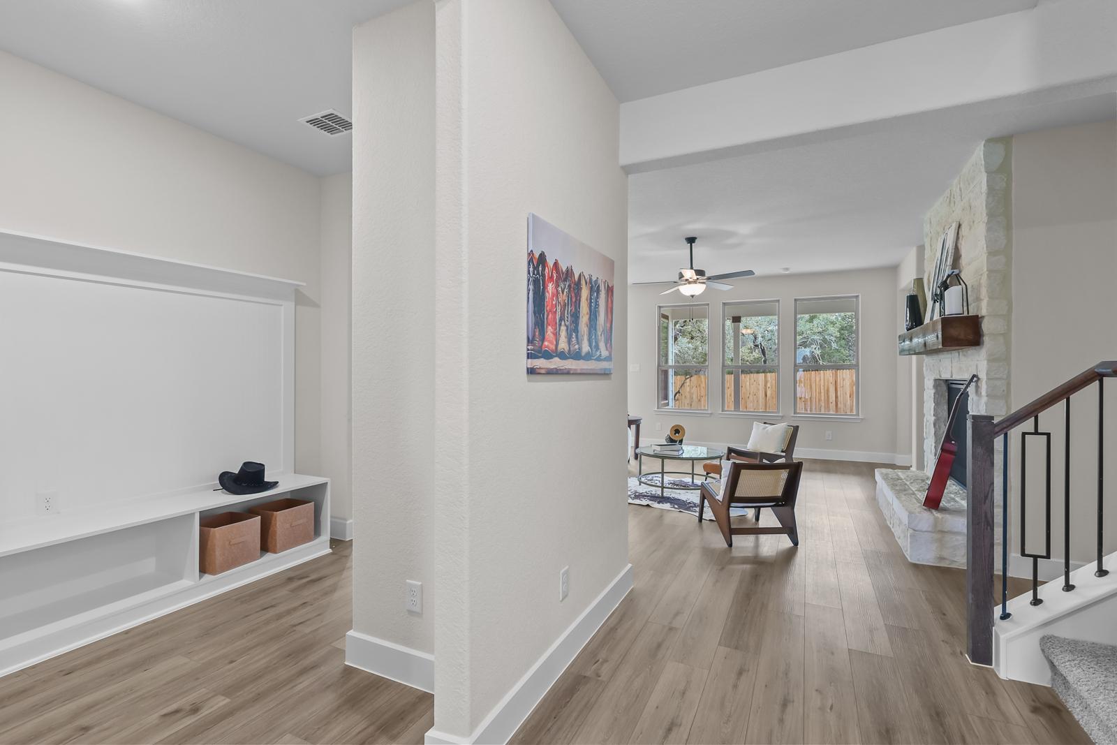Open-concept living area in The Belmont featuring a stone fireplace, wood flooring, and a built-in media center.