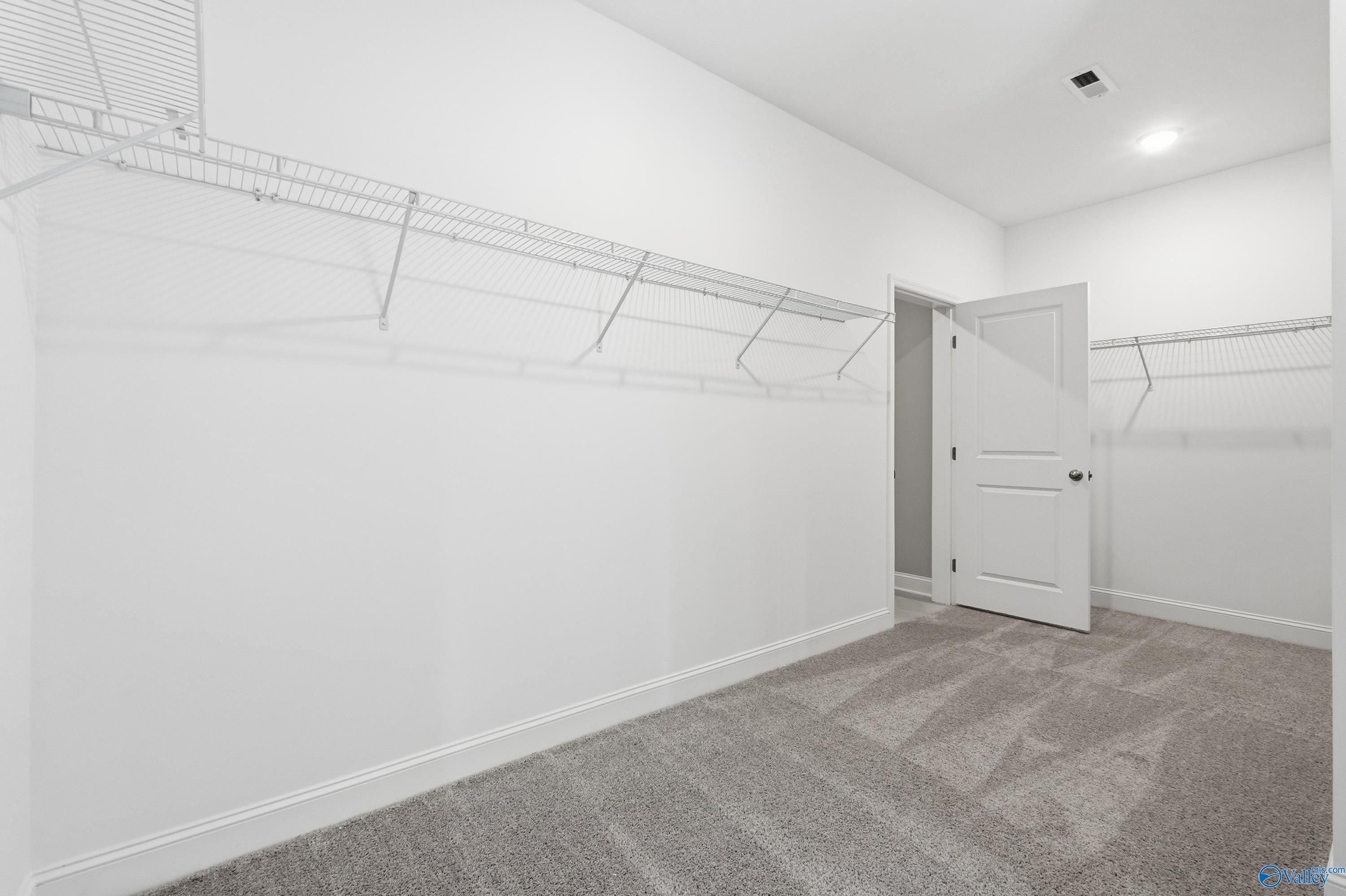 Spacious walk-in closet with wire shelving and hanging rods in Davidson Homes The Rockford master suite, Harvest, Alabama