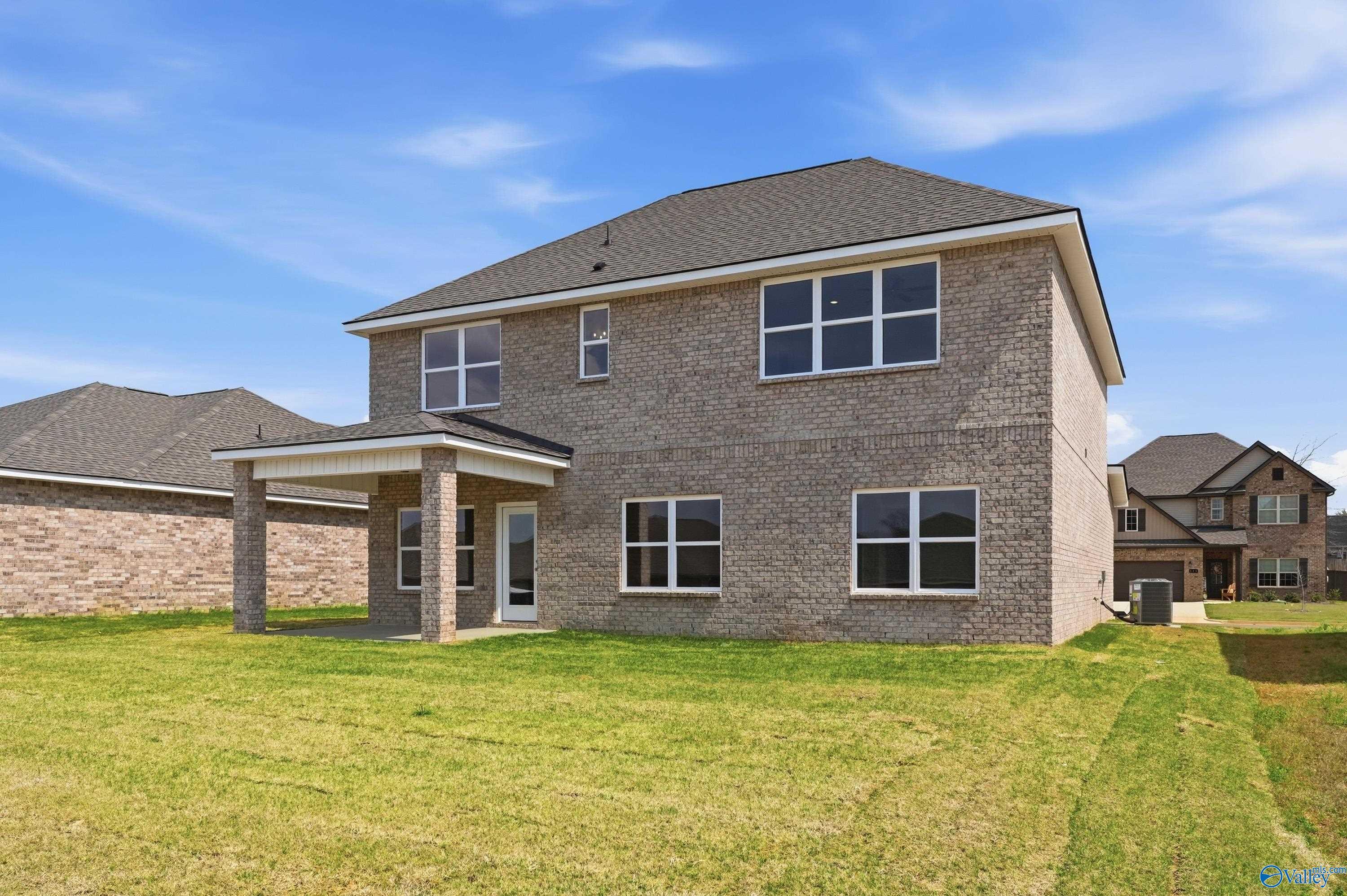 Two-story brick home with covered back patio, large windows, and green lawn in Creek Grove, New Market, Alabama