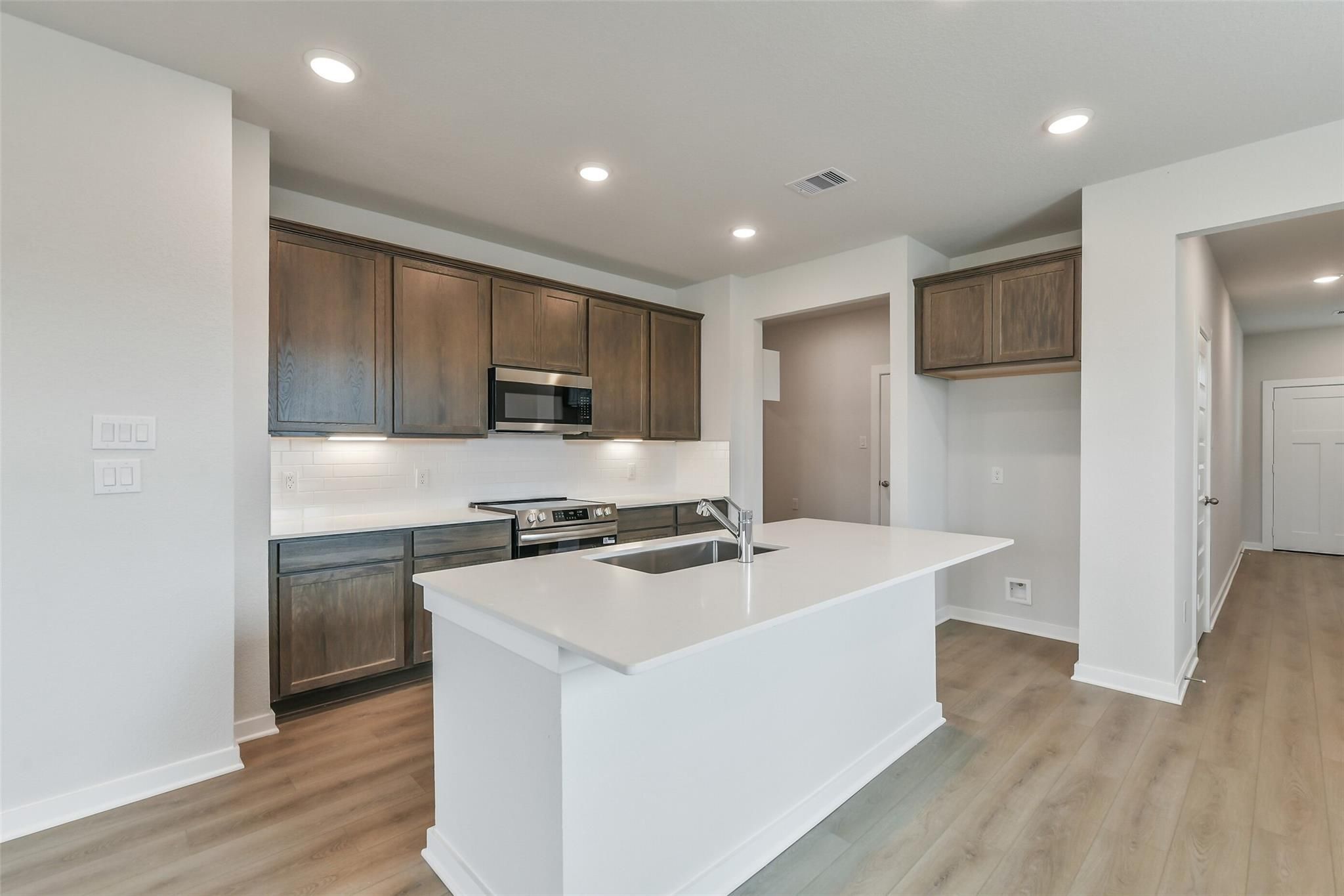 Modern kitchen with white quartz island, shaker cabinets, stainless appliances in Davidson Homes The Brazos E, Cleveland TX