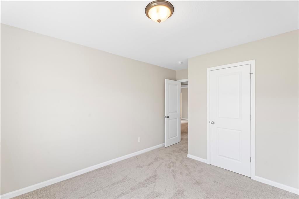 Cozy bedroom with beige walls, tan carpet, white doors, and flush-mount ceiling light in Davidson Homes The Washington, Phenix City