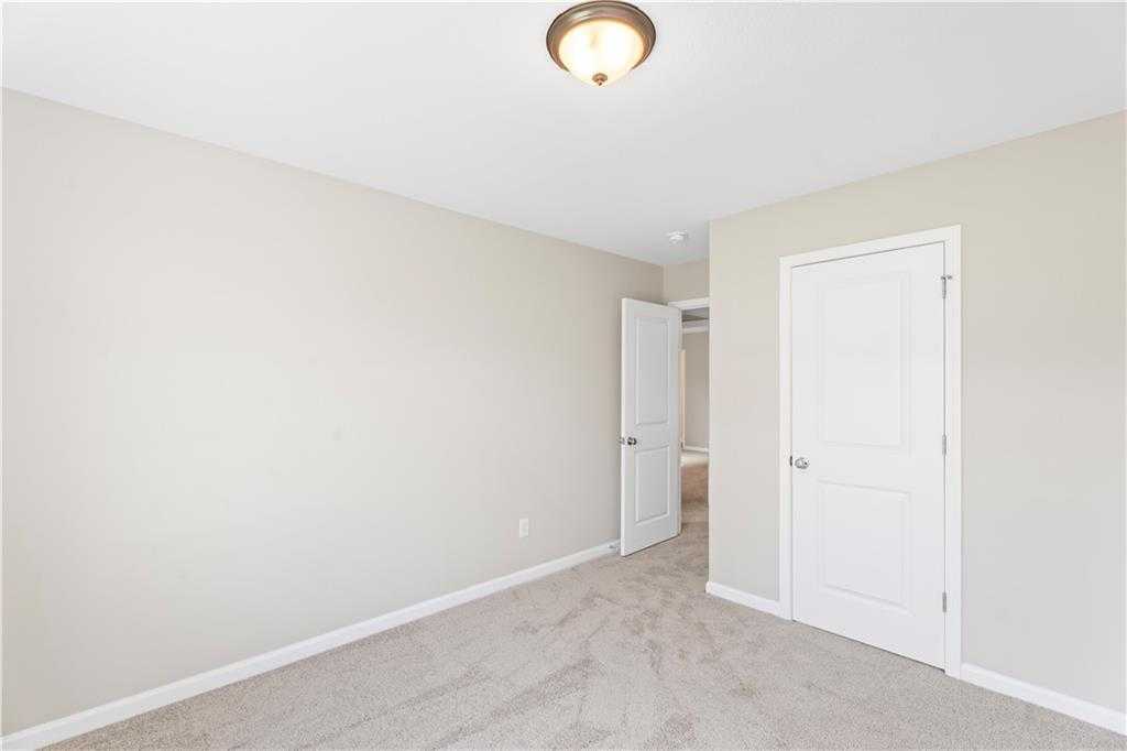 Cozy bedroom with beige walls, tan carpet, white doors, and flush-mount ceiling light in Davidson Homes The Washington, Phenix City