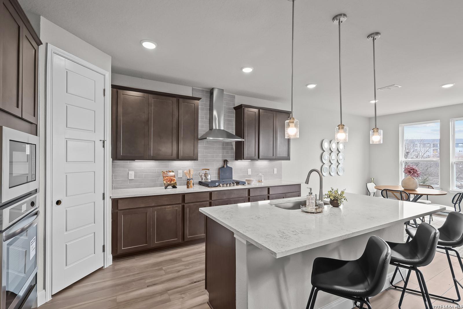 Modern kitchen featuring dark wood cabinets, white quartz island, stainless appliances in Davidson Homes The Rockford G, Ladera, San Antonio