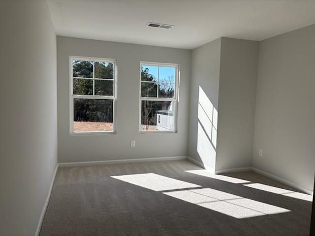 Sunlit secondary bedroom with light gray walls, beige carpet, and large windows overlooking trees in Davidson Homes Marion A, Winder, Georgia
