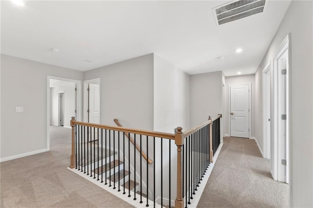 Spacious upstairs hallway with wooden railing staircase in The Marion A 3-bedroom home by Davidson Homes, Winder, Georgia