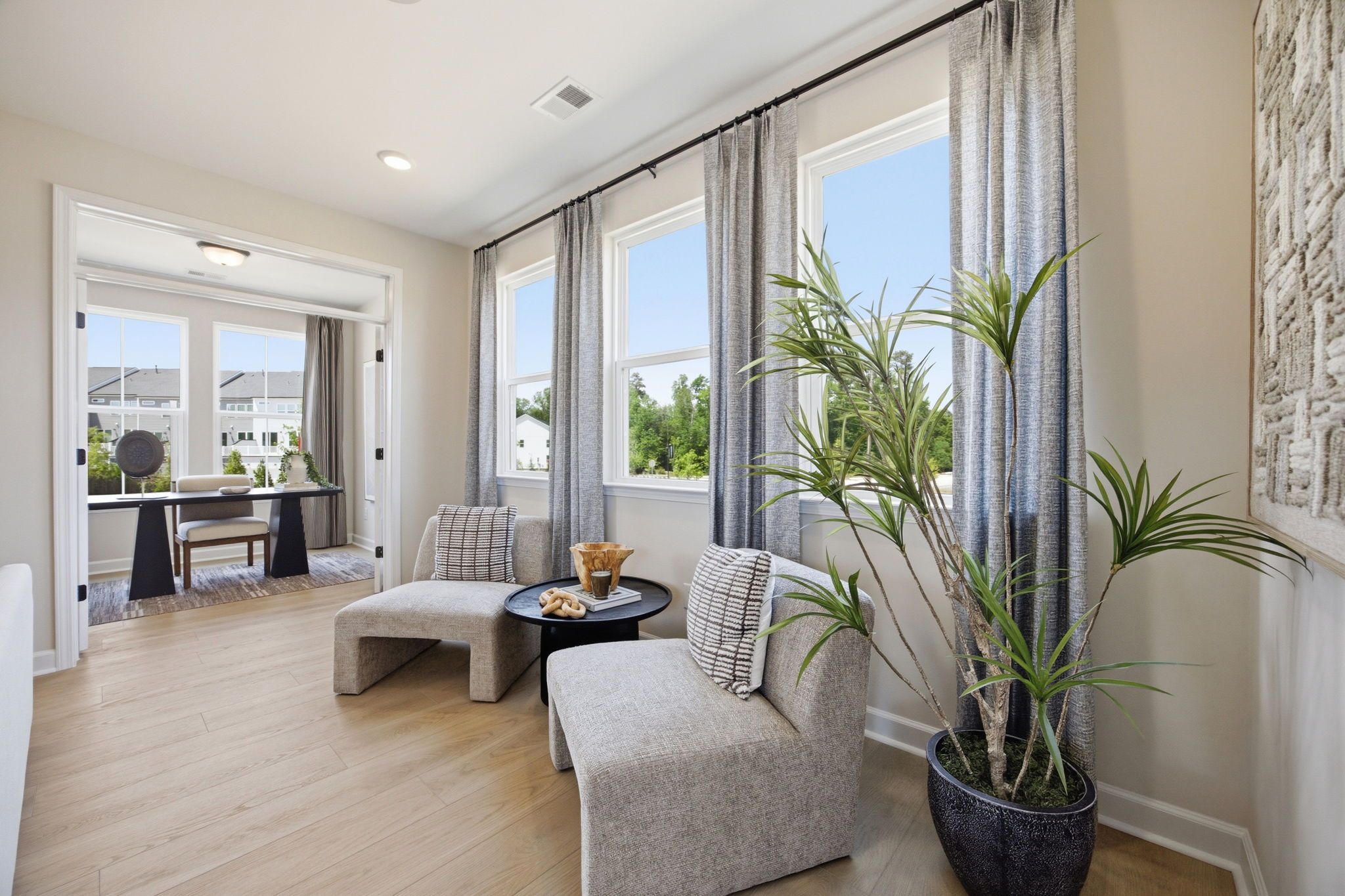 Bright sitting area with modern armchairs and hardwood floors at Forestville Yard in Knightdale, NC by Davidson Homes.