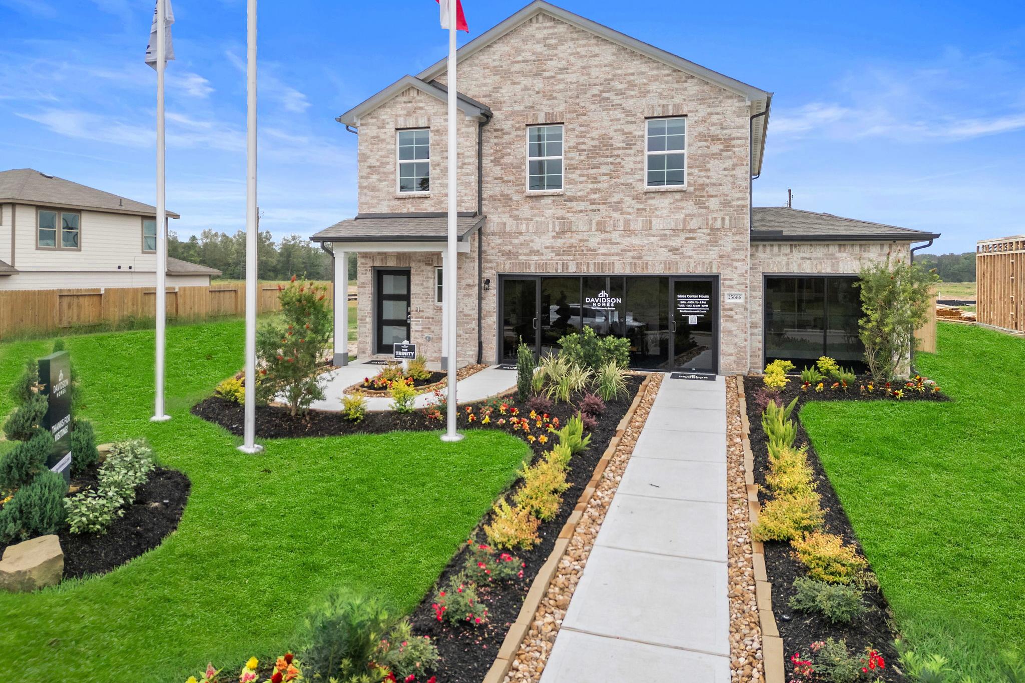 Brick home exterior with covered porch, US and Texas flags, landscaped yard at Hill & Dale Ranch in Splendora Texas