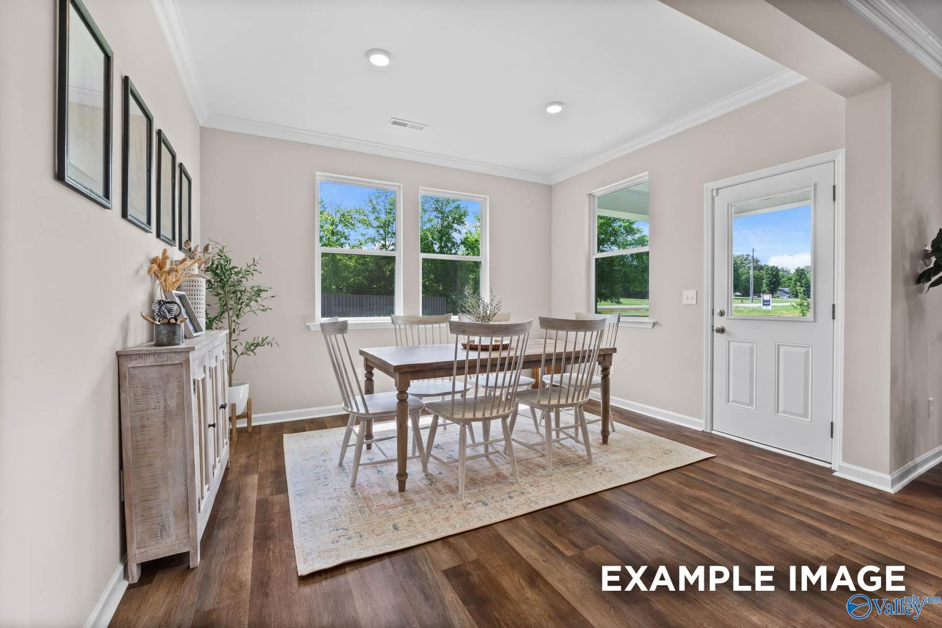 Elegant dining room featuring wooden table, chairs, large windows with tree views, and beige walls in The Arcadia by Evermore Homes, Owens Cross Roads
