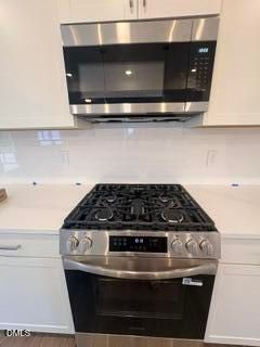 Modern kitchen with stainless steel gas range and microwave in The Willow B floor plan at Woodland Crossing, Zebulon, NC.